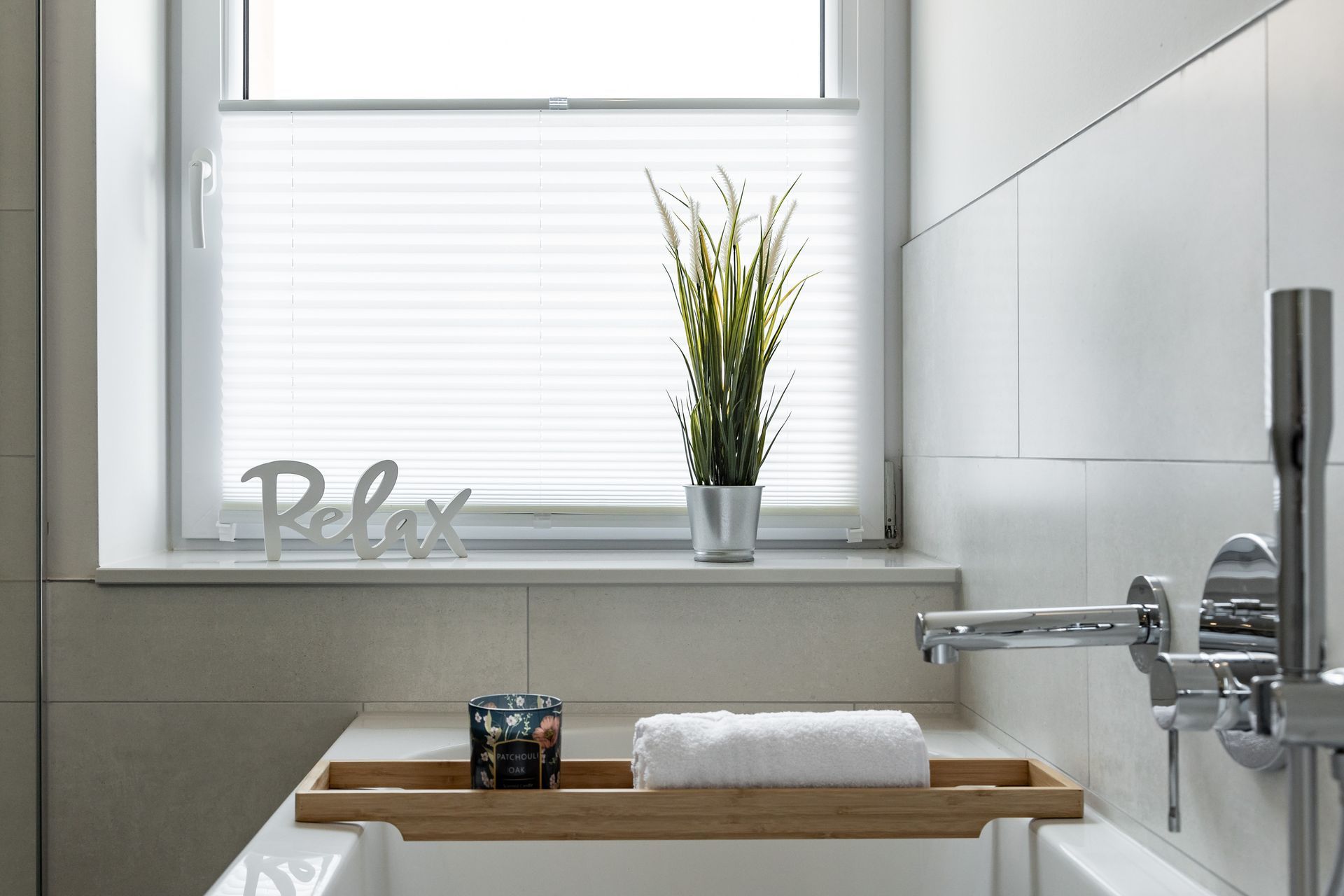 A bathroom with a bathtub and a window with a plant on the window sill.