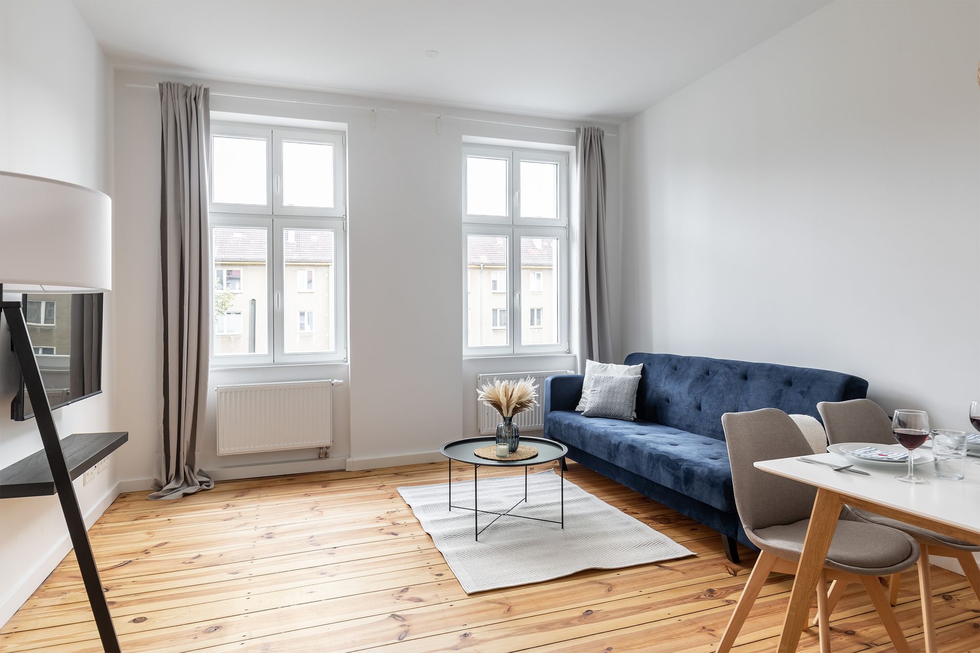 A living room with a blue couch , table and chairs.