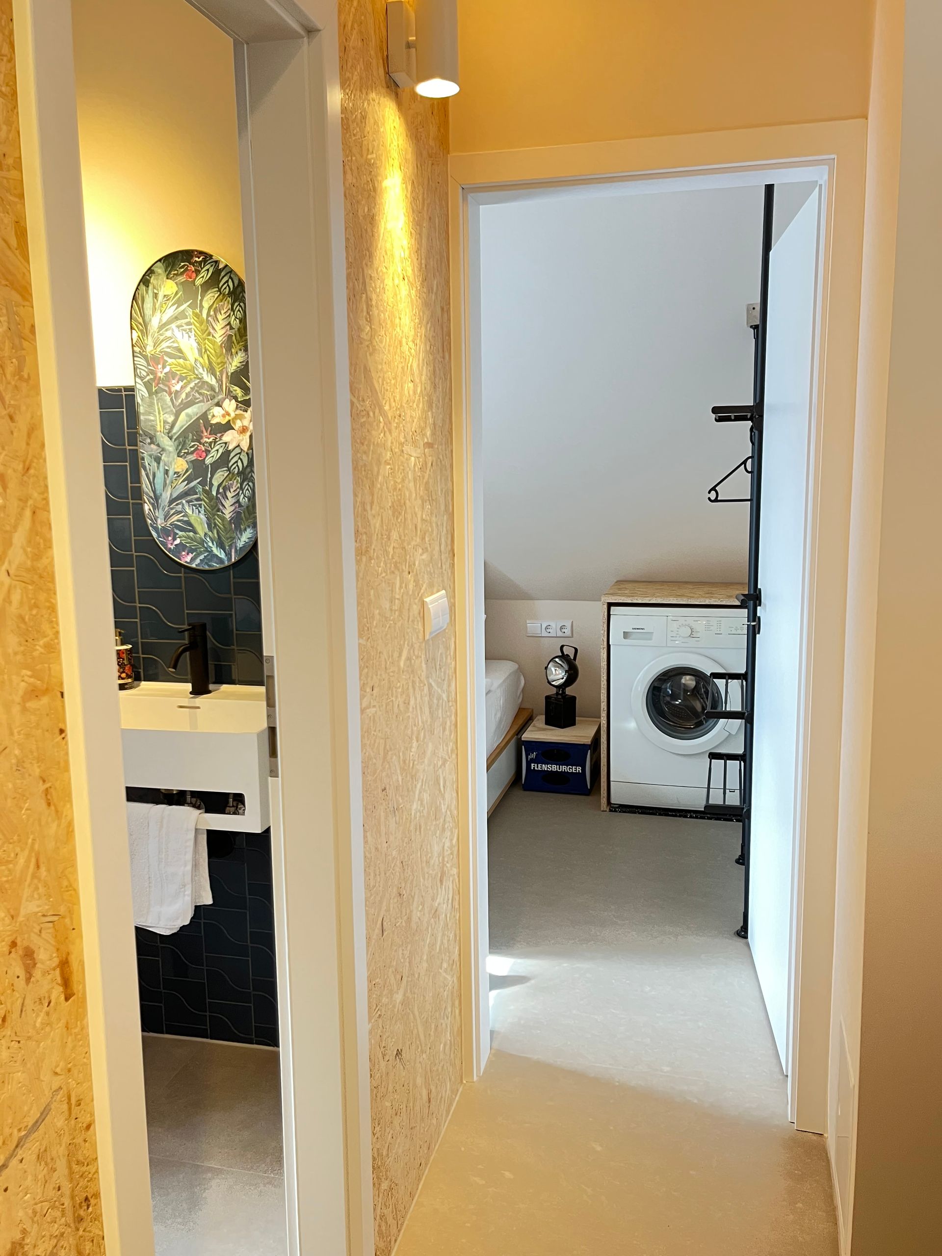A hallway leading to a bathroom with a sink and a washer and dryer.