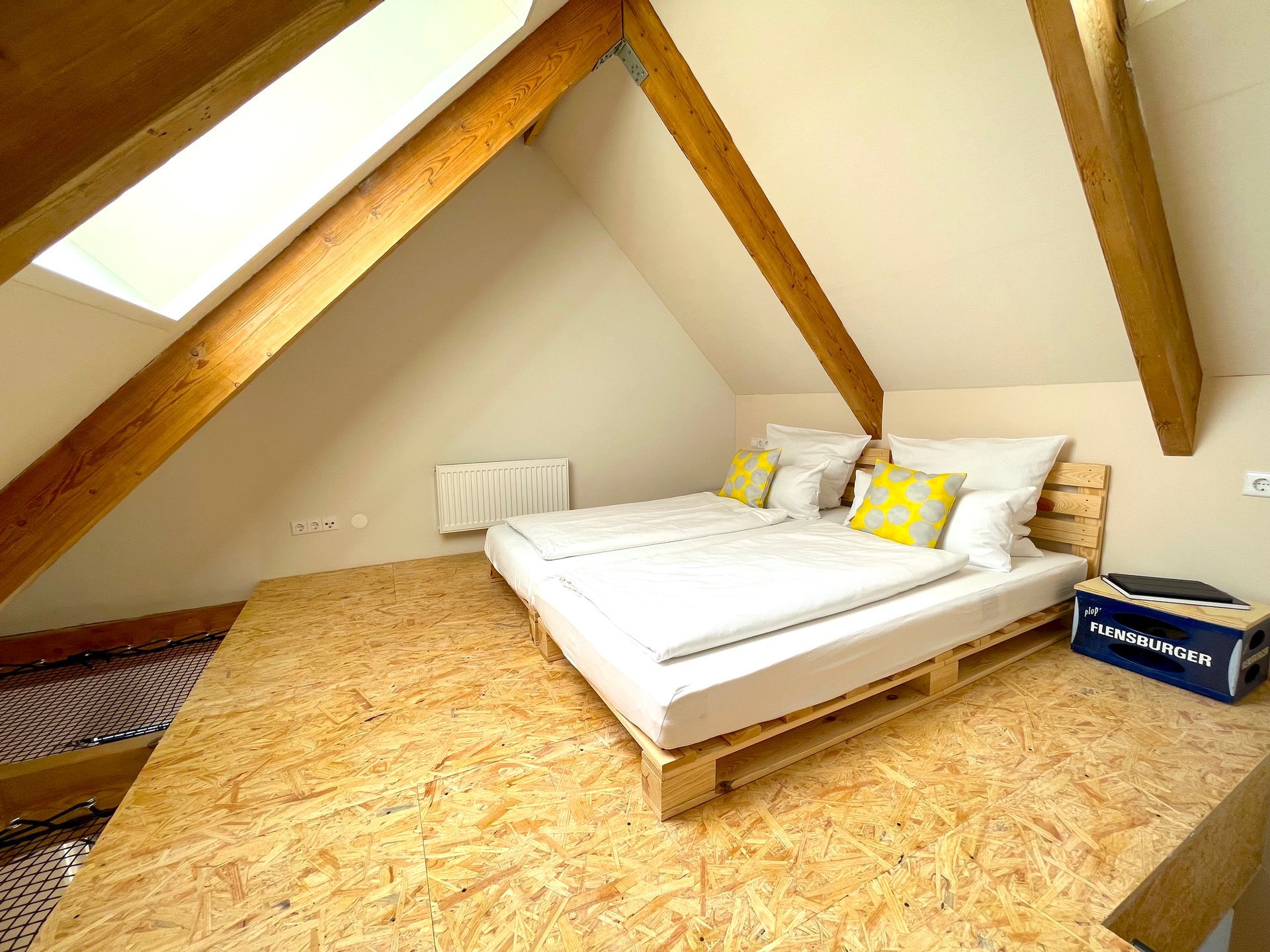There are two beds in the attic with wooden beams.