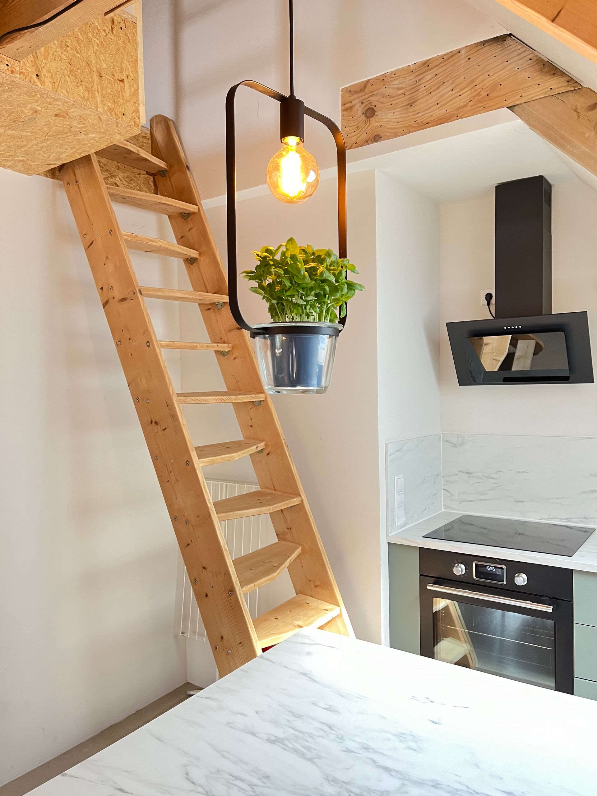 A kitchen with a wooden staircase leading up to the second floor