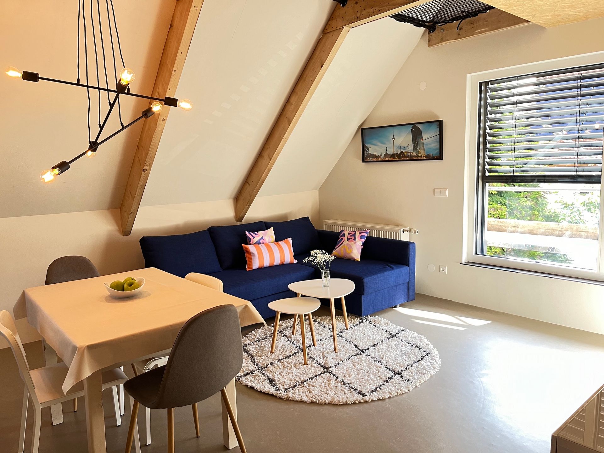 A living room with a blue couch , table and chairs.