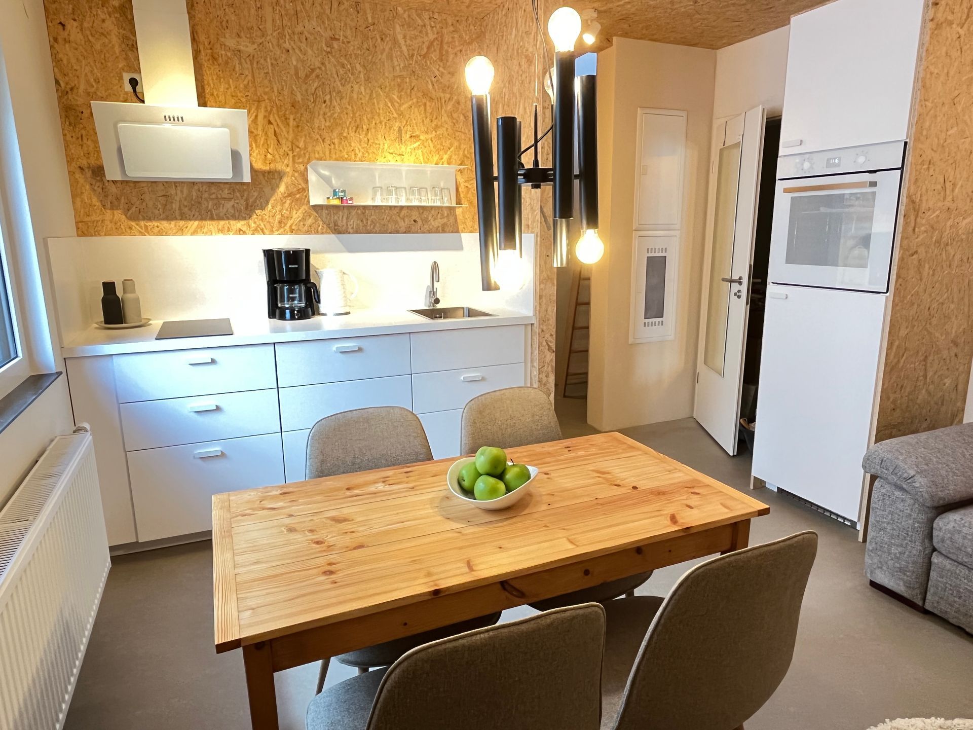 A kitchen with a table and chairs and a bowl of apples on it