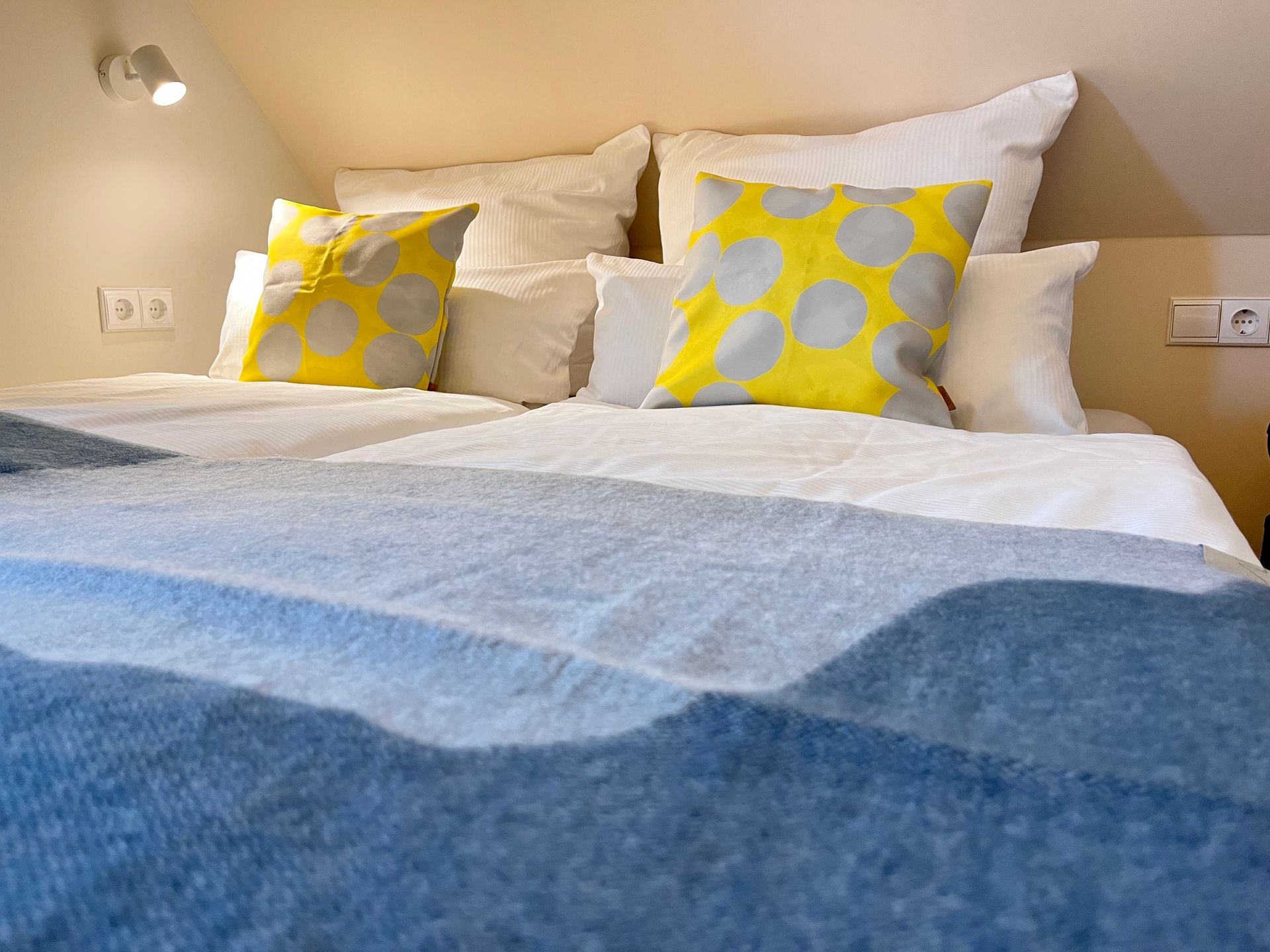 A bed with a blue blanket and yellow pillows on it.