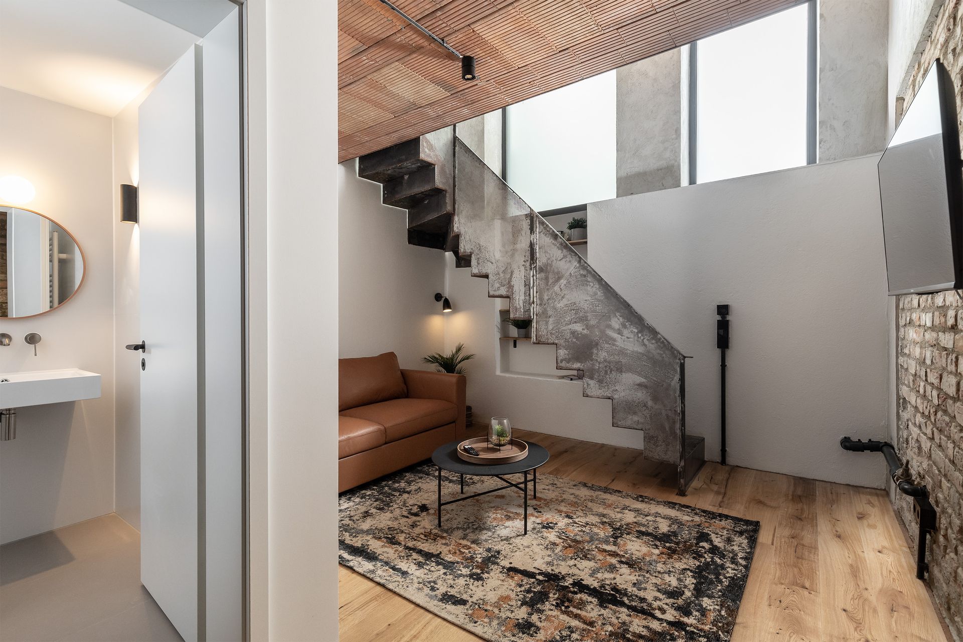 A living room with a couch and stairs leading up to the second floor.
