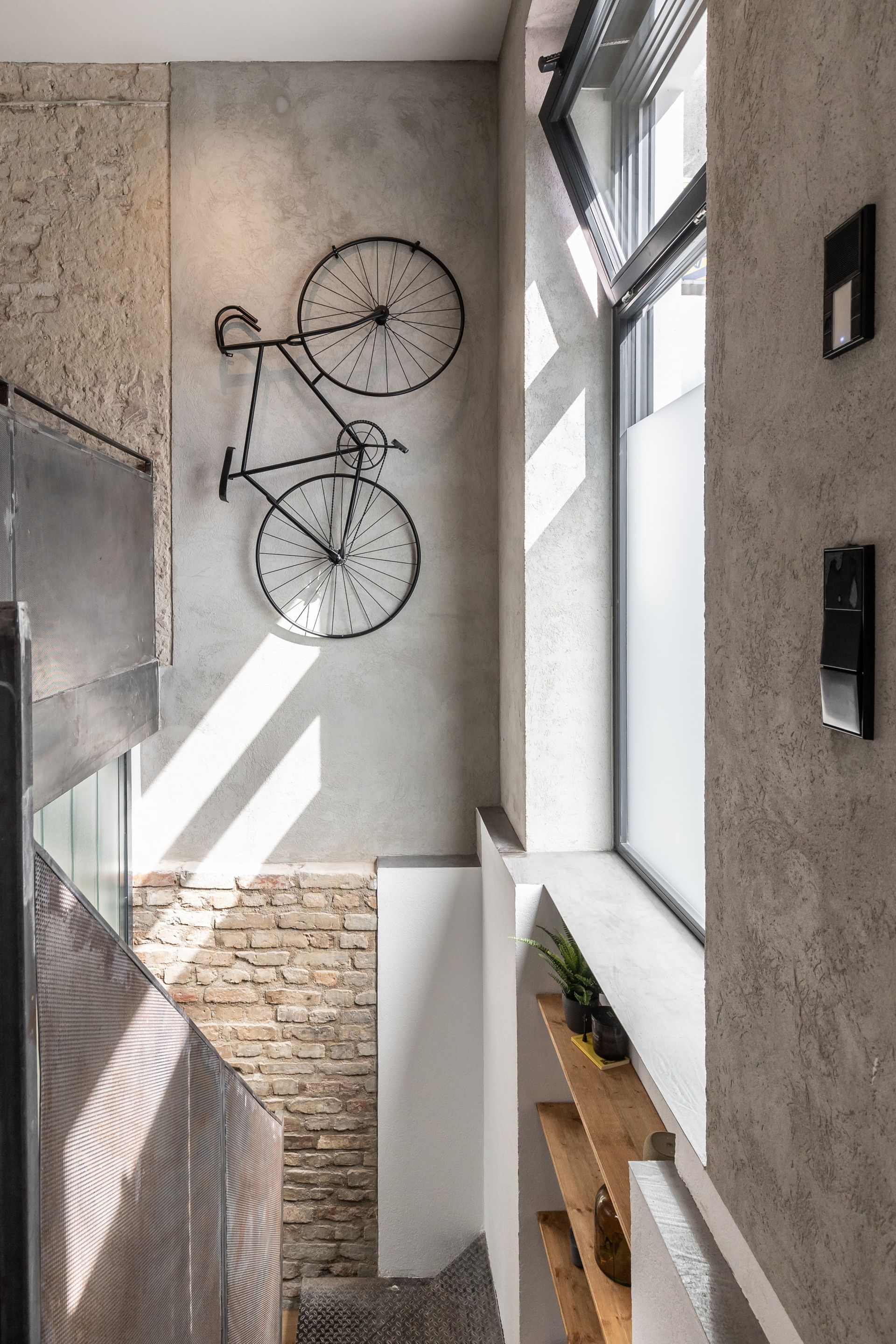 A bicycle is hanging on a wall next to a window.