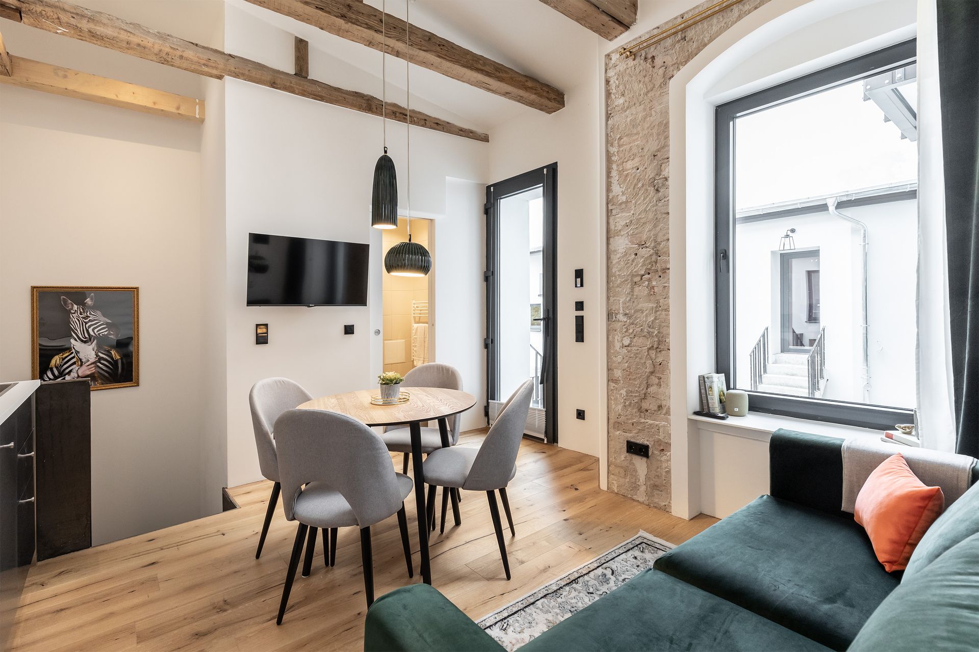 A living room with a green couch , a table and chairs.