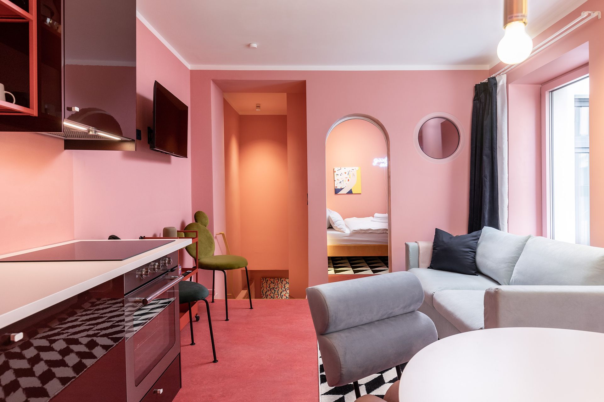 A living room with pink walls and a white couch.