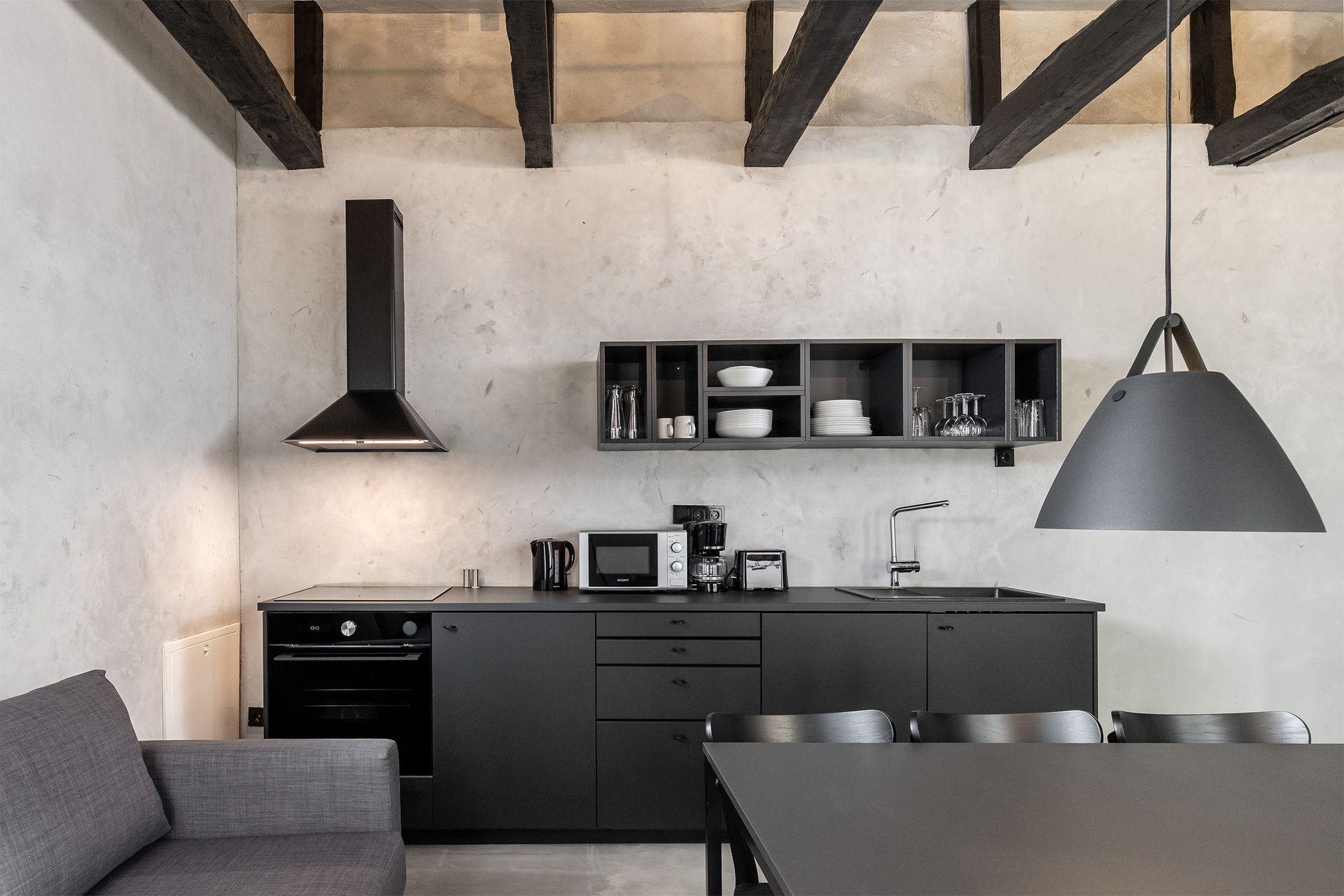 A kitchen with black cabinets and a gray couch
