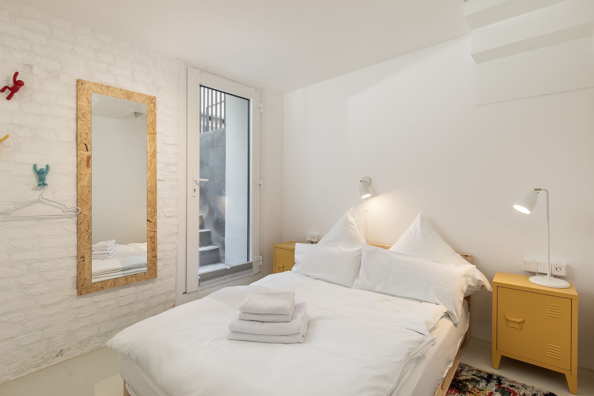 A bedroom with a bed , nightstand , and mirror.