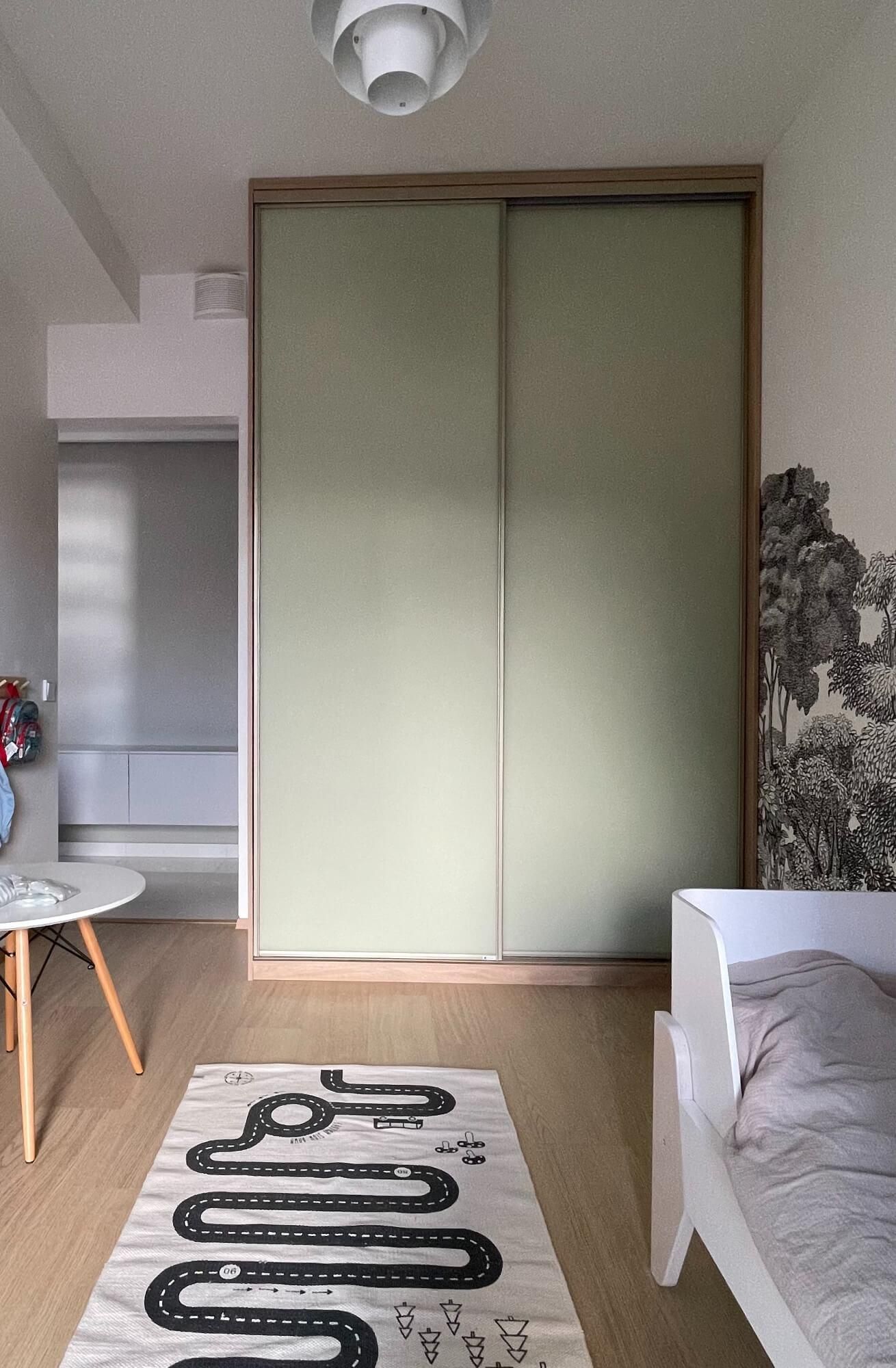 Maalaistalotyylinen keittiö, jossa on salvianvihreät kaapistot, valkoinen esiliina-allas, puiset työtasot ja valkoinen metrolaattainen välitila.