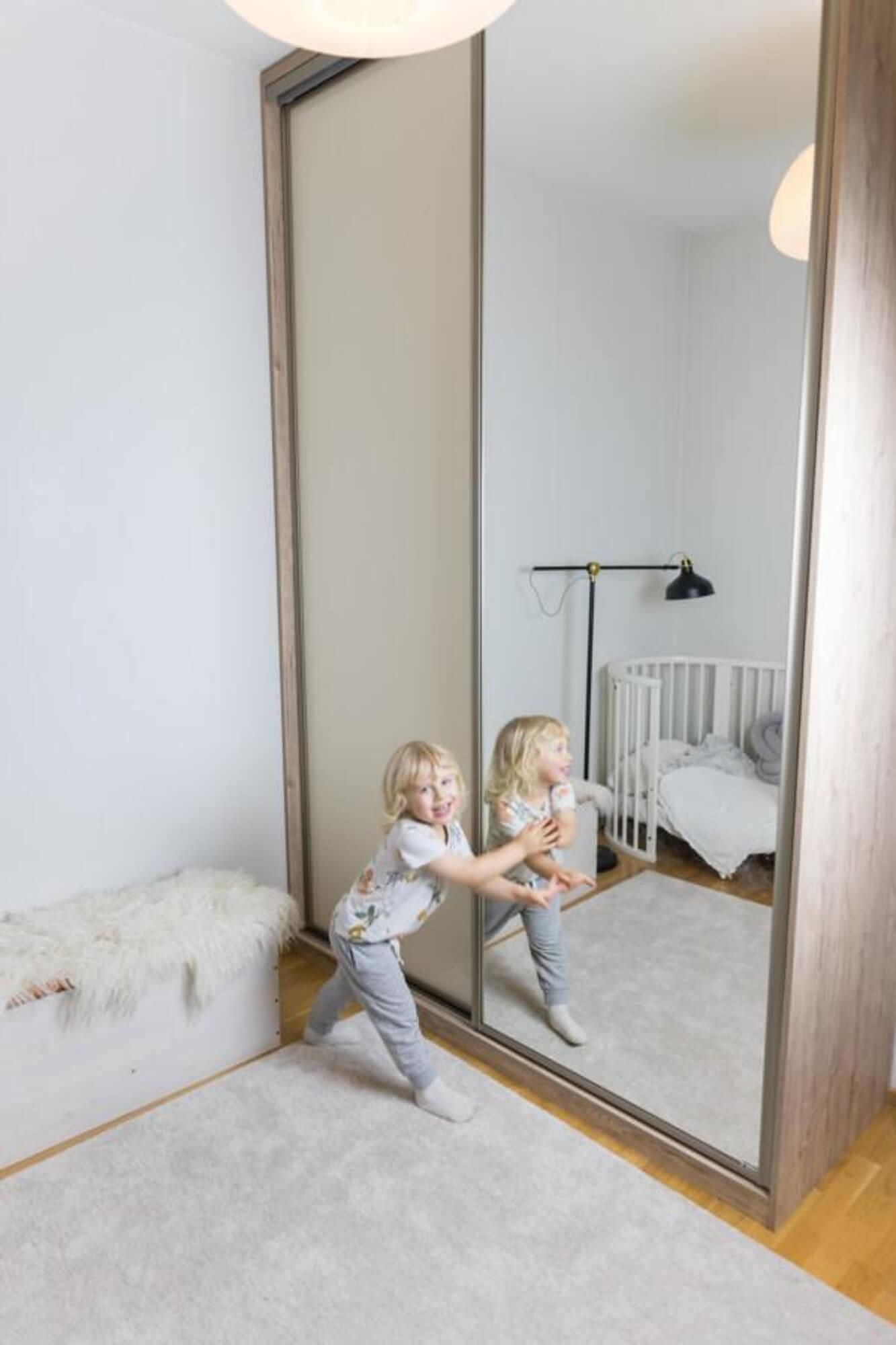 Moderni keittiö, jossa mattamustat kaapistot, saareke, ruostumattomasta teräksestä valmistettu jääkaappi ja vaalea puulattia.