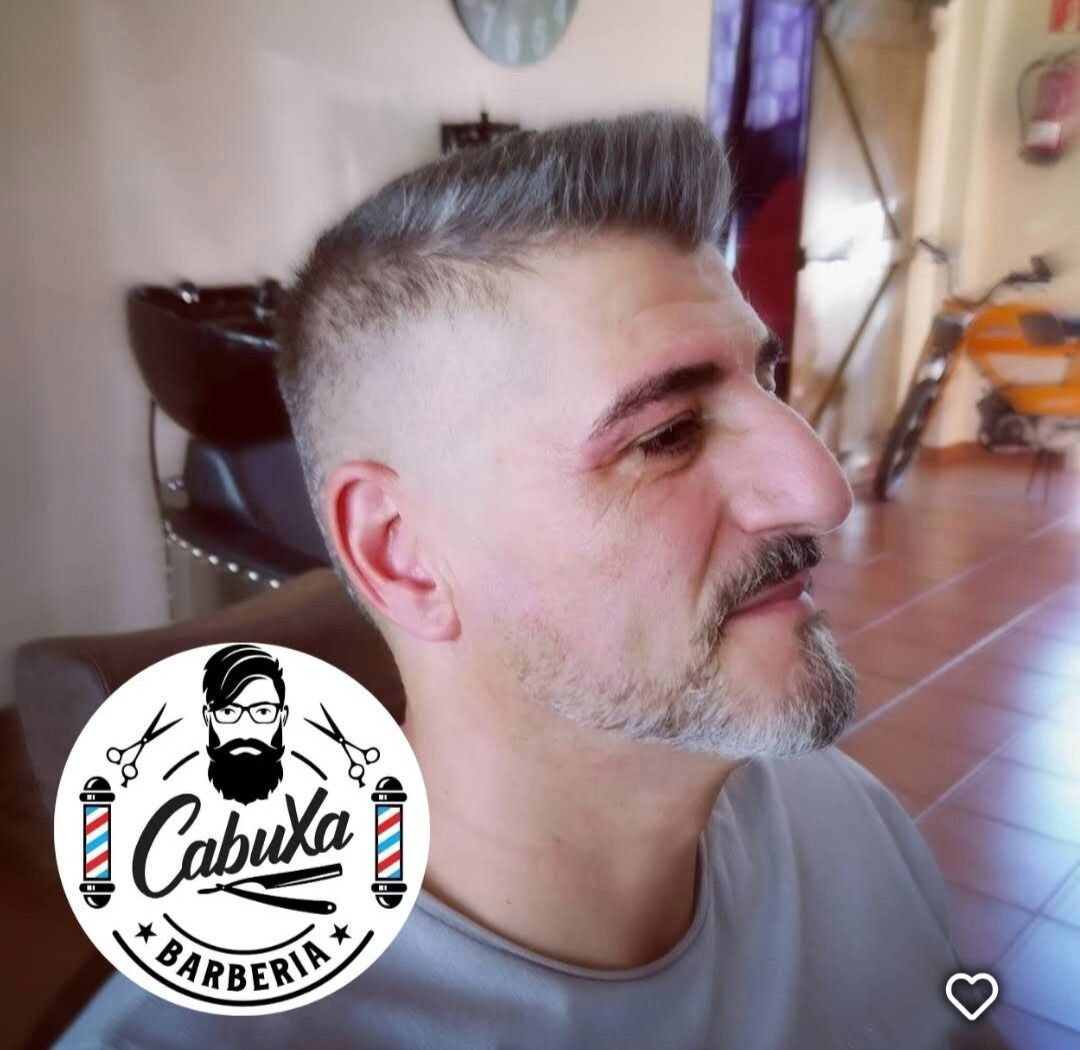Un hombre con barba se está cortando el pelo en una barbería.
