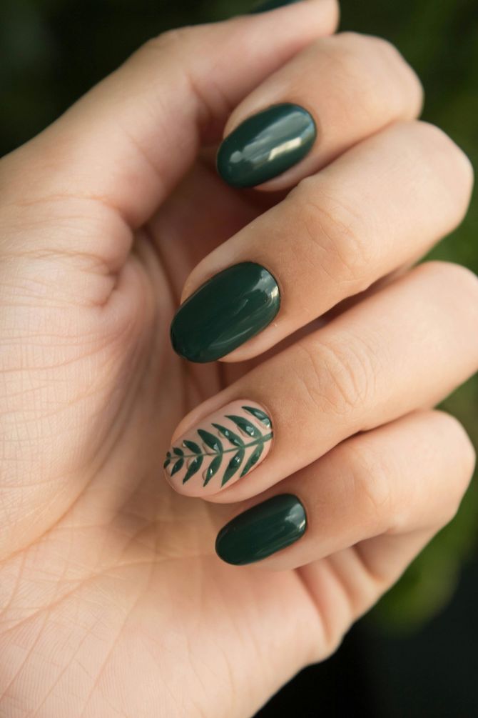 Un primer plano de la mano de una mujer con uñas verdes y un diseño de hojas.