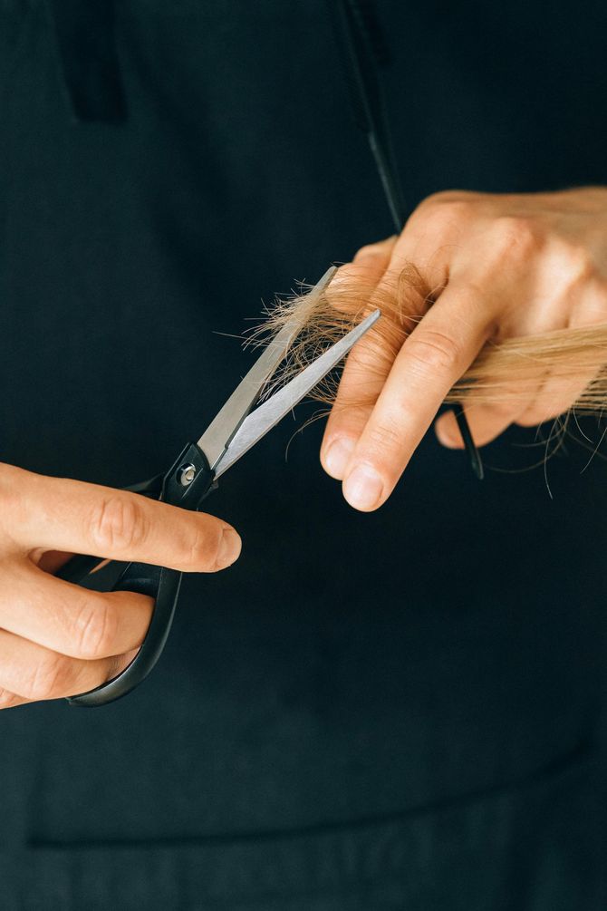 Una persona se está cortando el pelo con unas tijeras.
