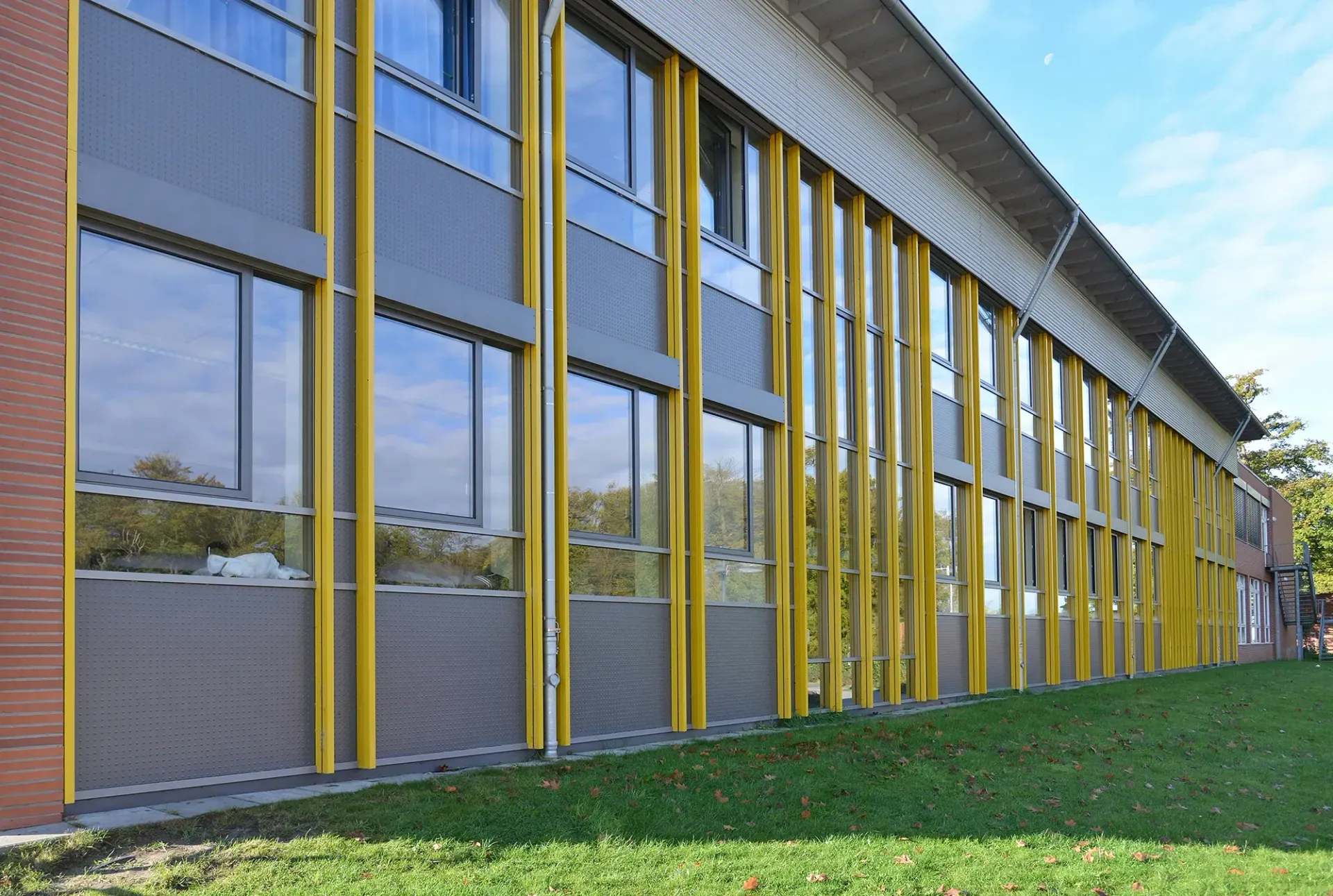 Ein großes Gebäude mit vielen Fenstern und einer Rasenfläche davor.