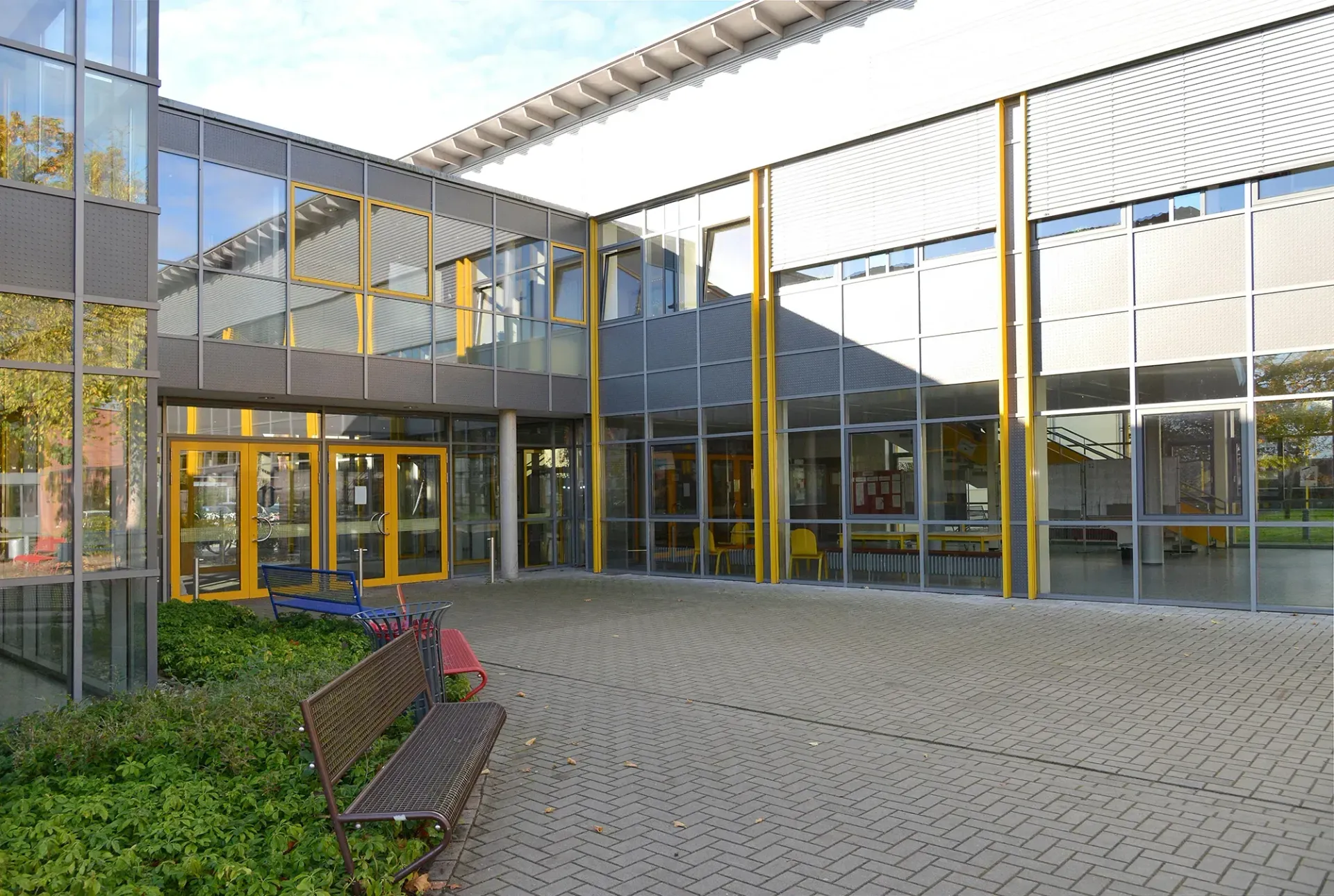 Ein großes Gebäude mit vielen Fenstern und einer Bank davor