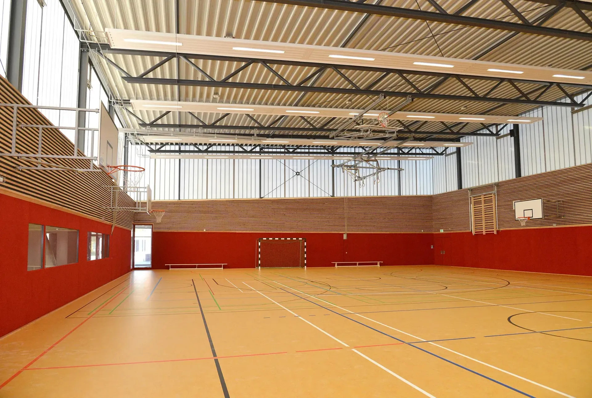 Ein großer Indoor-Basketballplatz mit einer roten Wand und einem Basketballkorb.