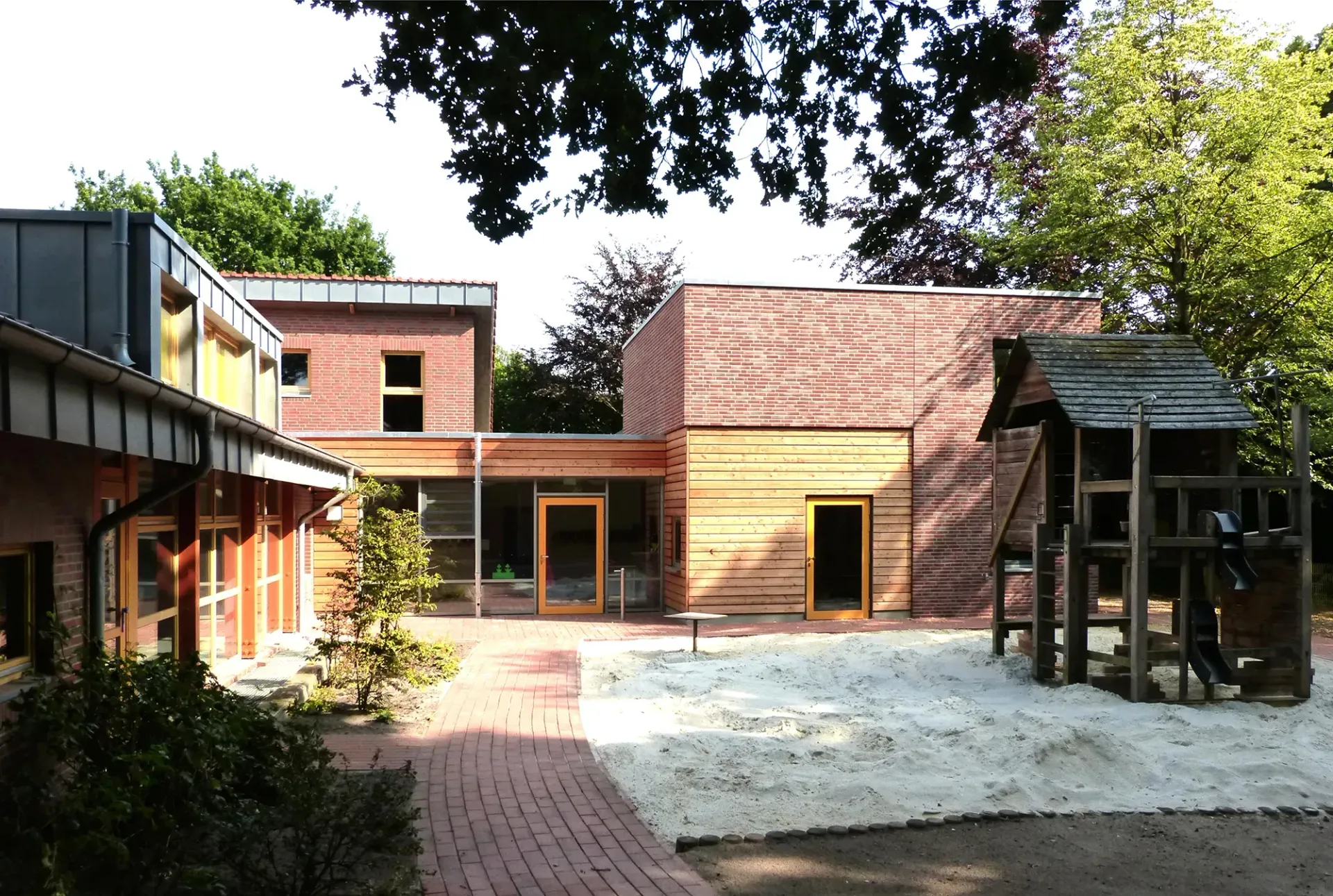 Ein Backsteingebäude mit einem Holzspielplatz davor