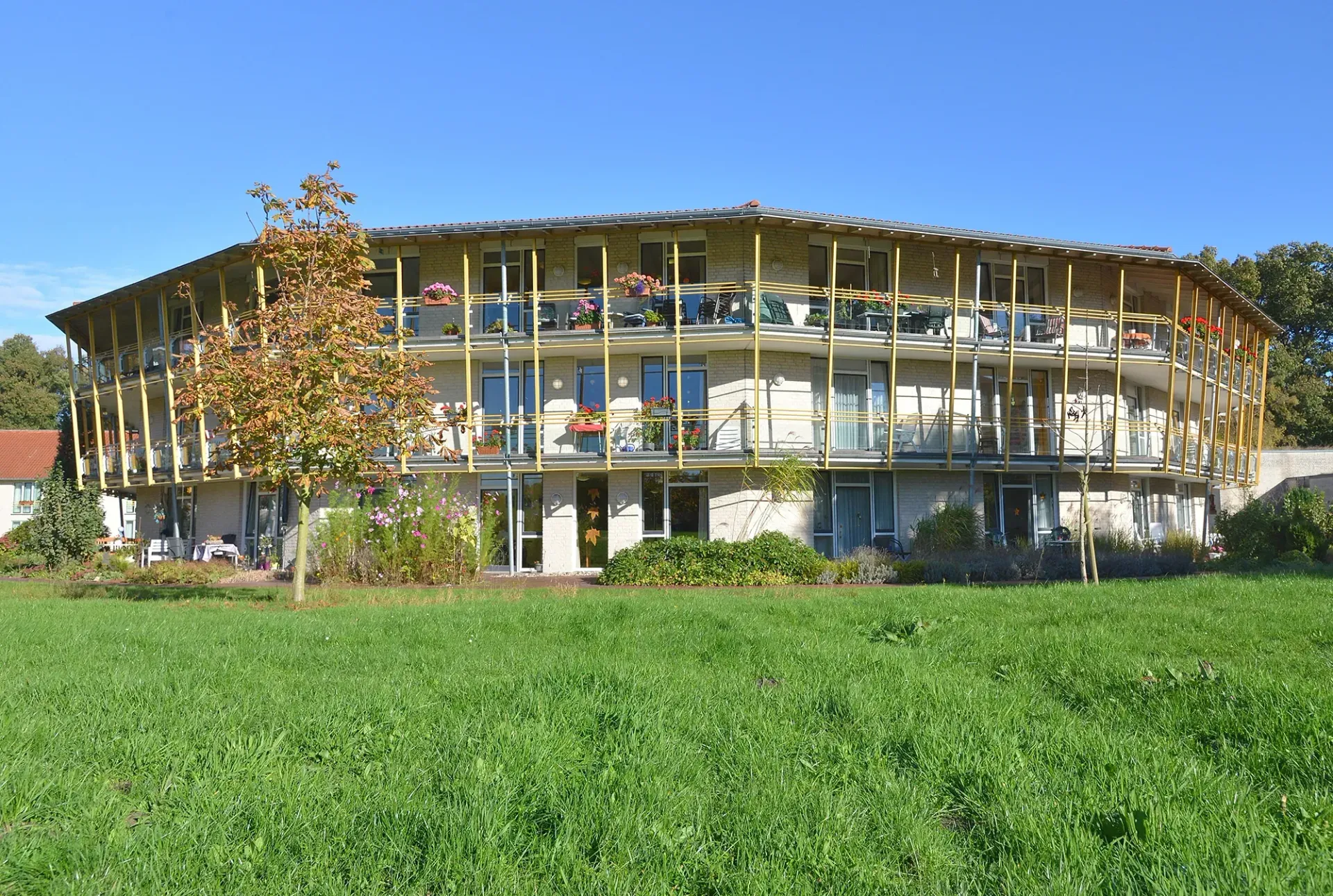 Ein großes Gebäude mit vielen Balkonen steht inmitten einer Wiese.