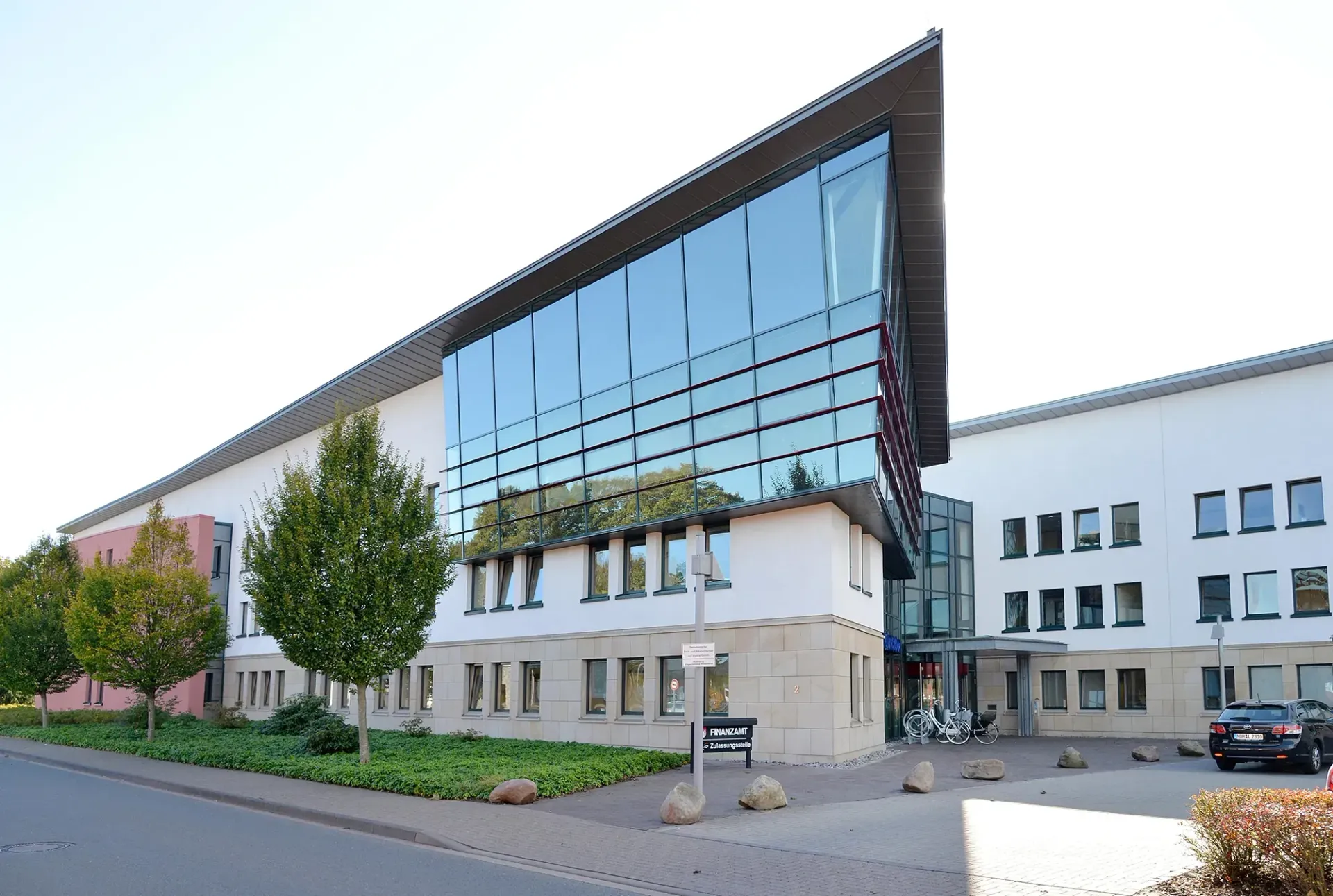 Ein großes Gebäude mit vielen Fenstern und einem davor geparkten Auto