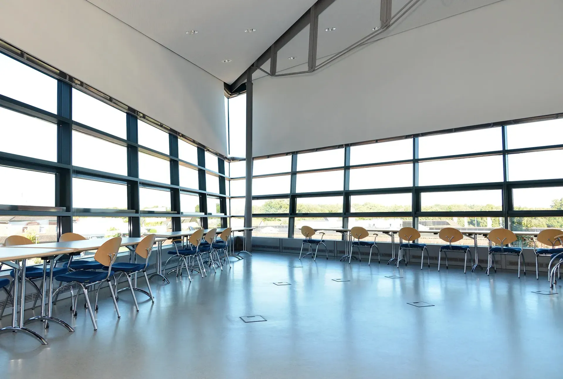 Ein großer Raum mit Tischen und Stühlen und vielen Fenstern