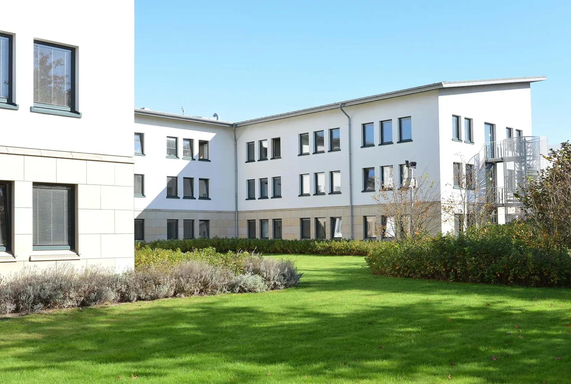 Ein großes weißes Gebäude mit vielen Fenstern und einem üppigen grünen Rasen davor