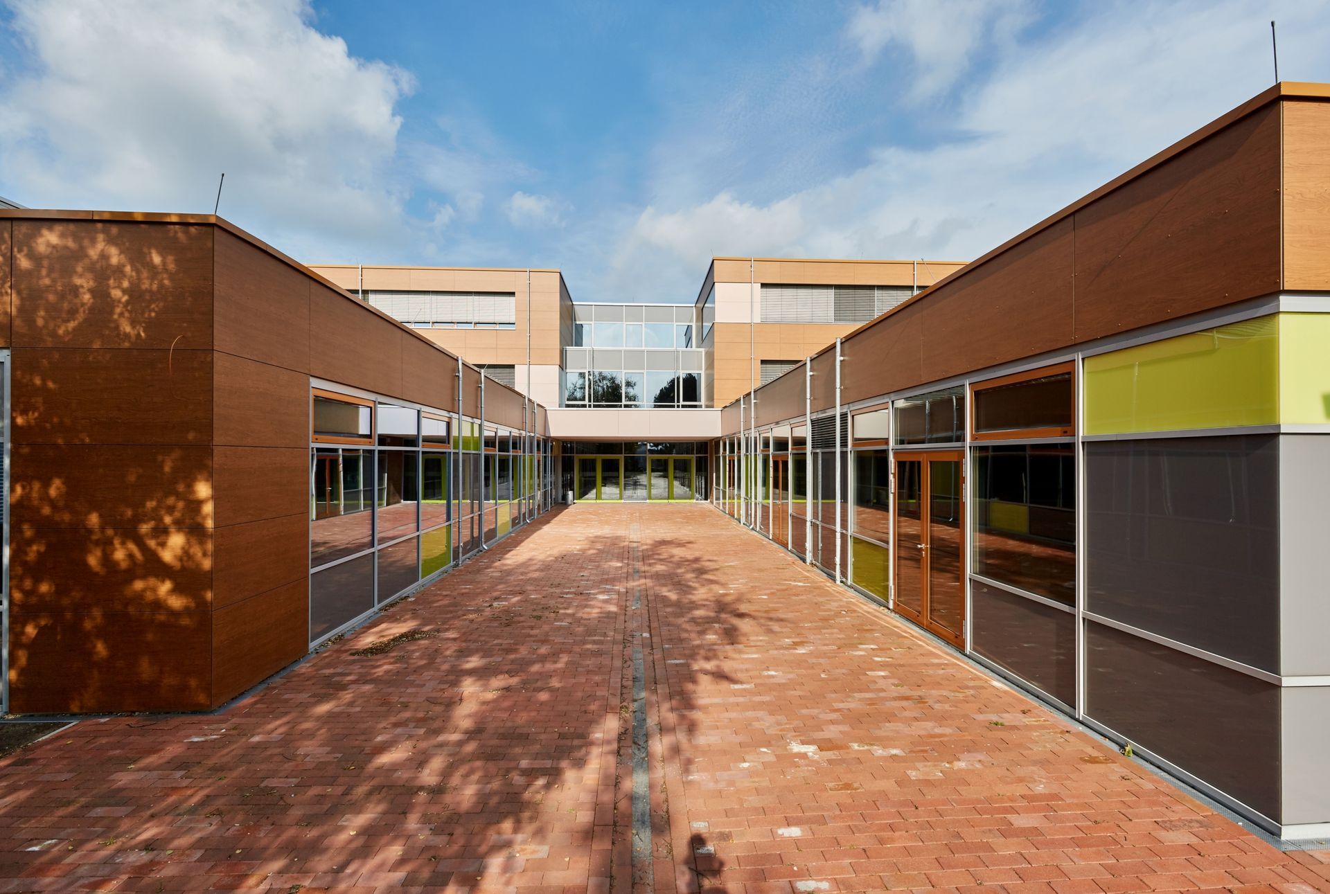Ein Ziegelweg zwischen zwei Gebäuden mit einem blauen Himmel im Hintergrund.