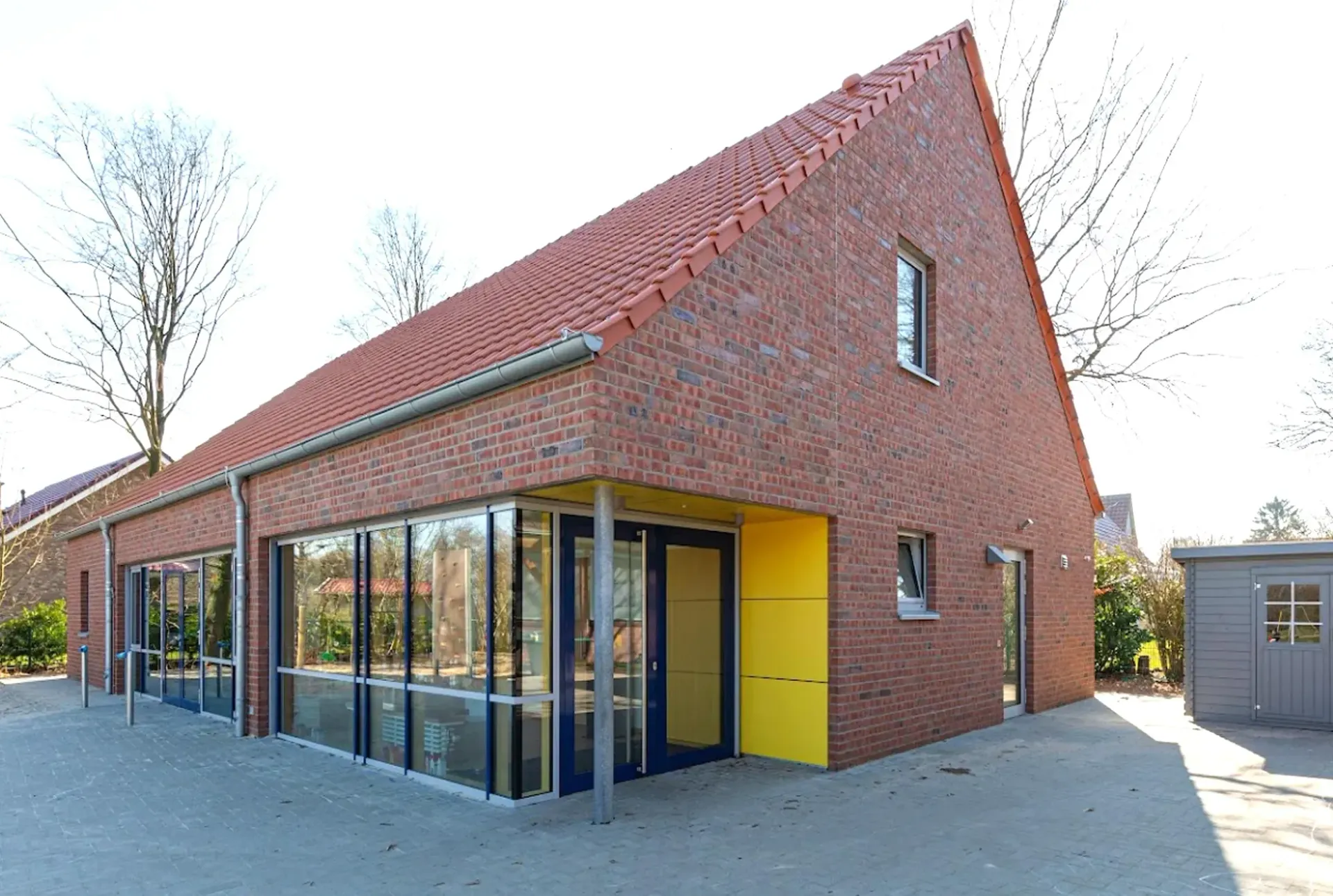 Ein Backsteingebäude mit einem roten Dach und einer gelben Tür.