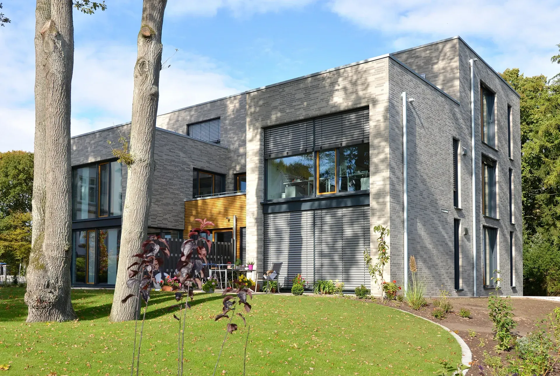 Ein großes Backsteingebäude mit vielen Fenstern ist von Bäumen umgeben.