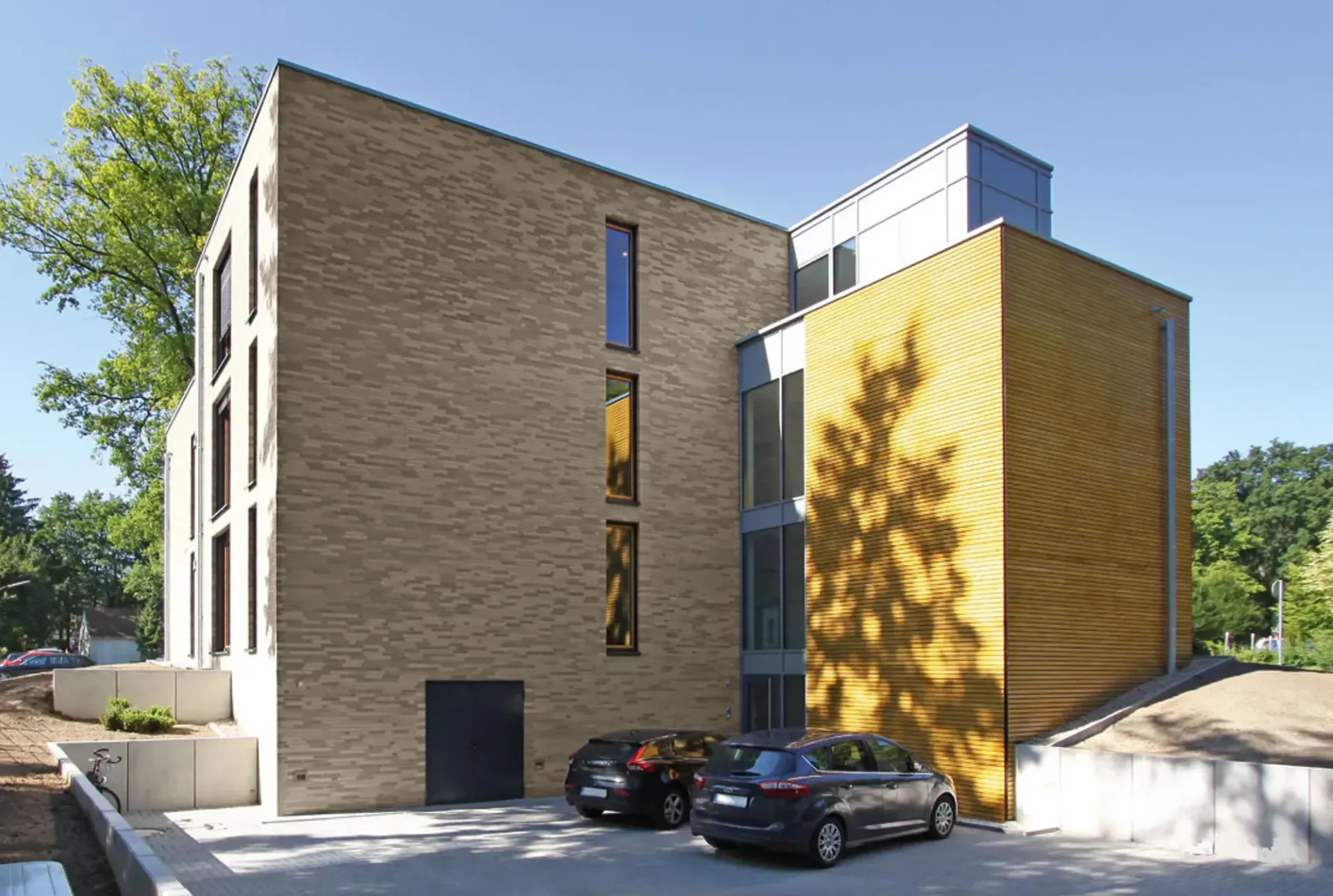 Zwei Autos sind vor einem großen Backsteingebäude geparkt.