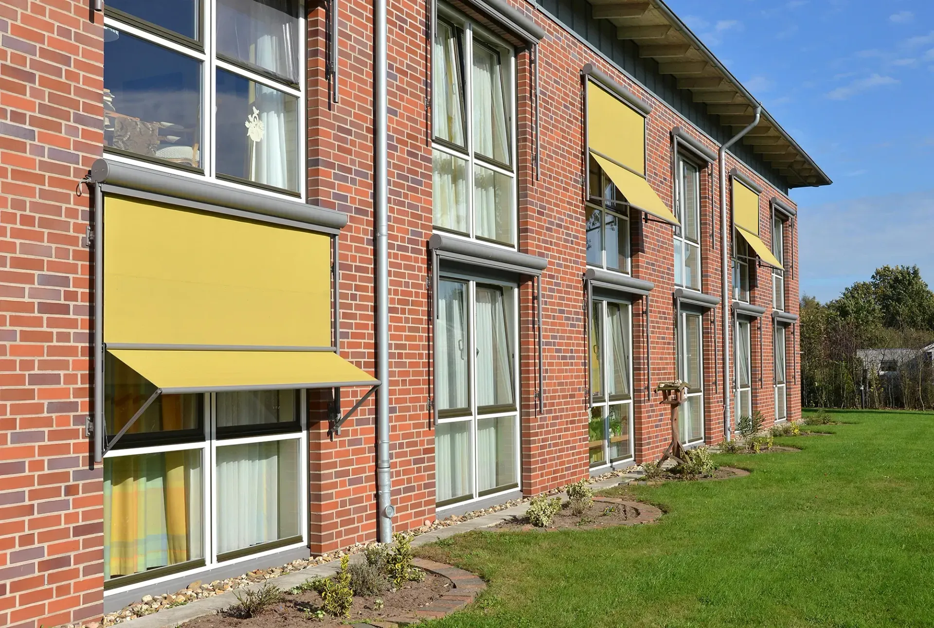 Ein Backsteingebäude mit gelben Markisen an den Fenstern