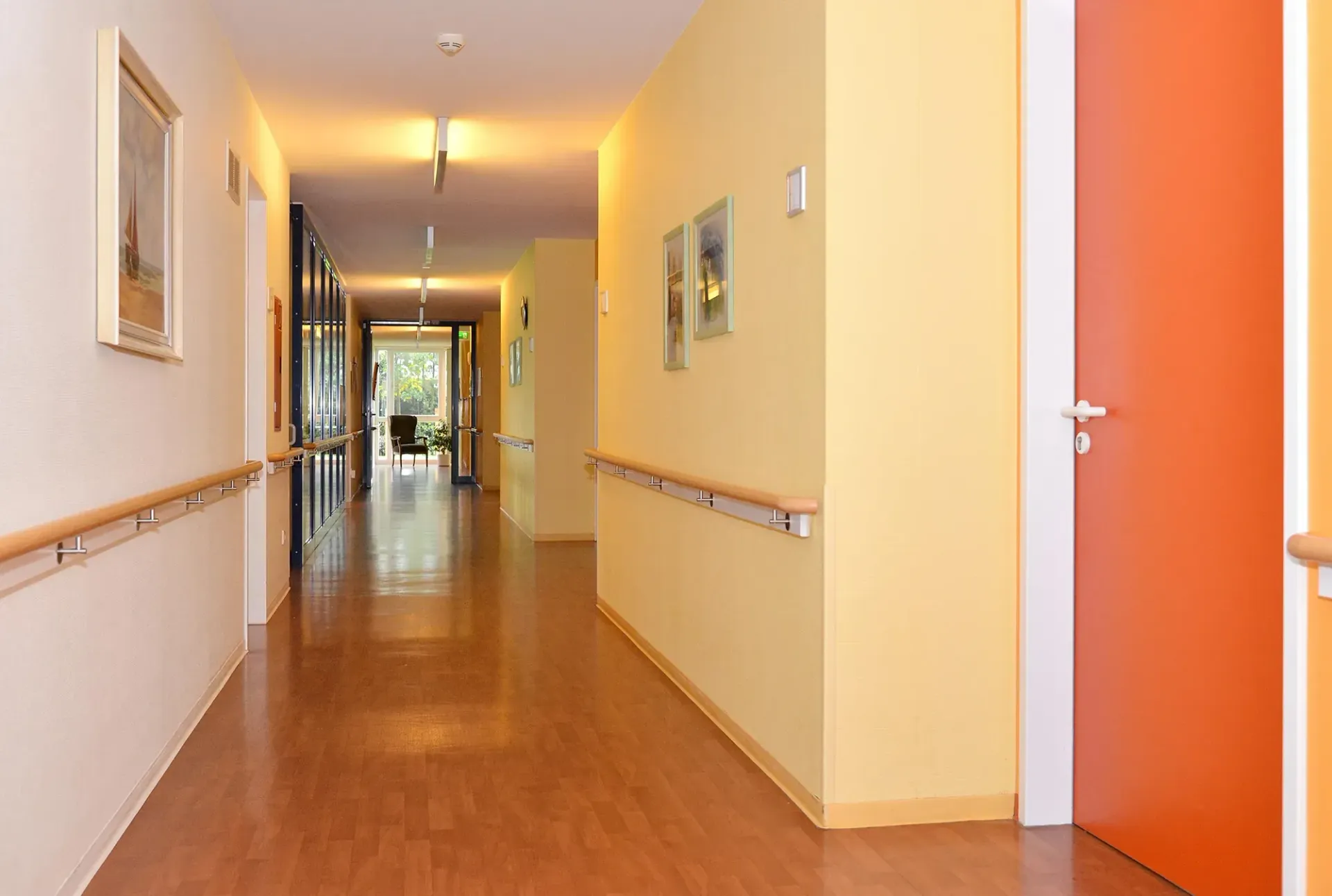 Ein langer Flur mit einer roten Tür und gelben Wänden