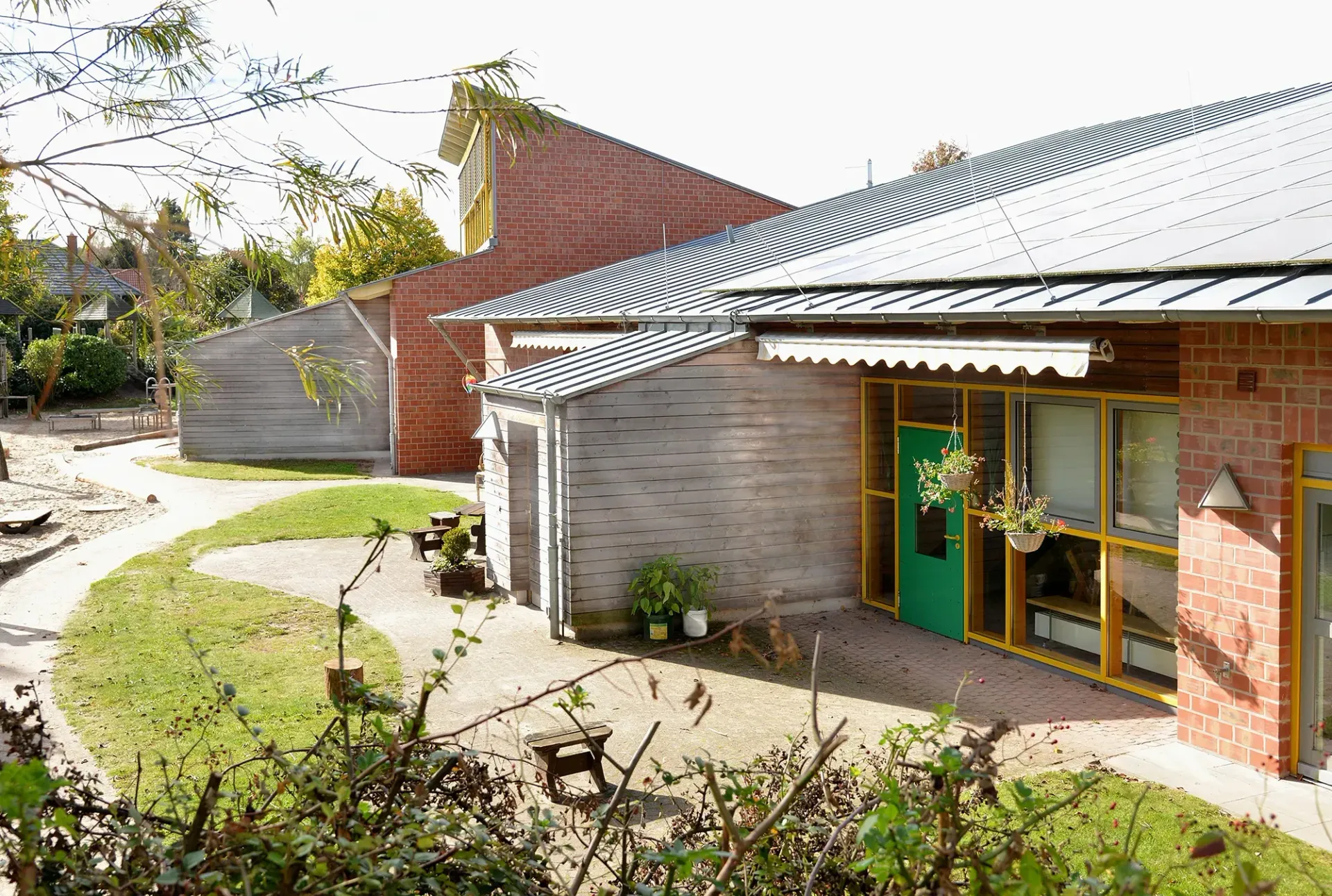 Ein Backsteingebäude mit einer grünen Tür und einer Terrasse davor.