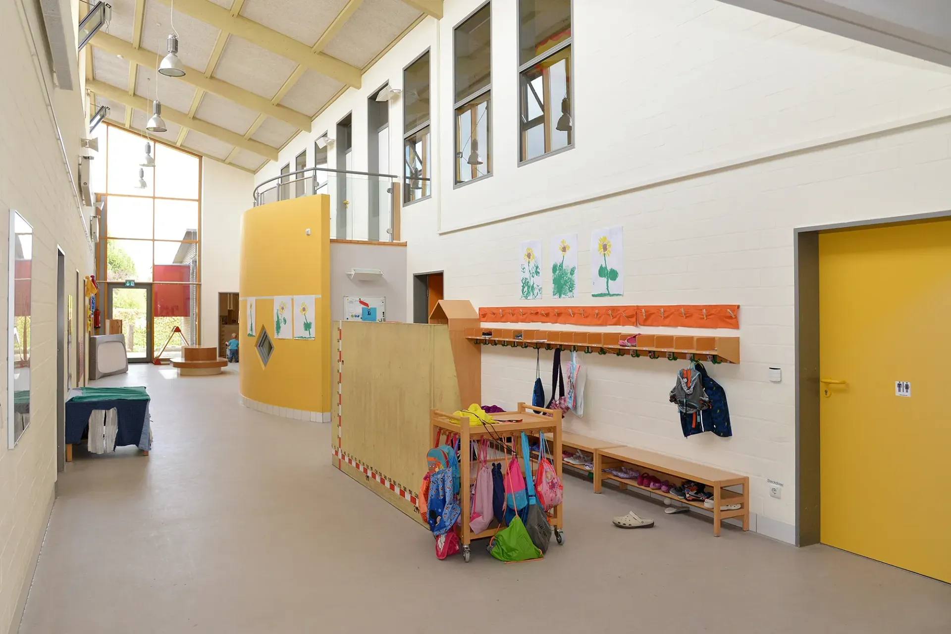 Ein Flur in einer Schule mit einer gelben Tür und einer Holzbank.