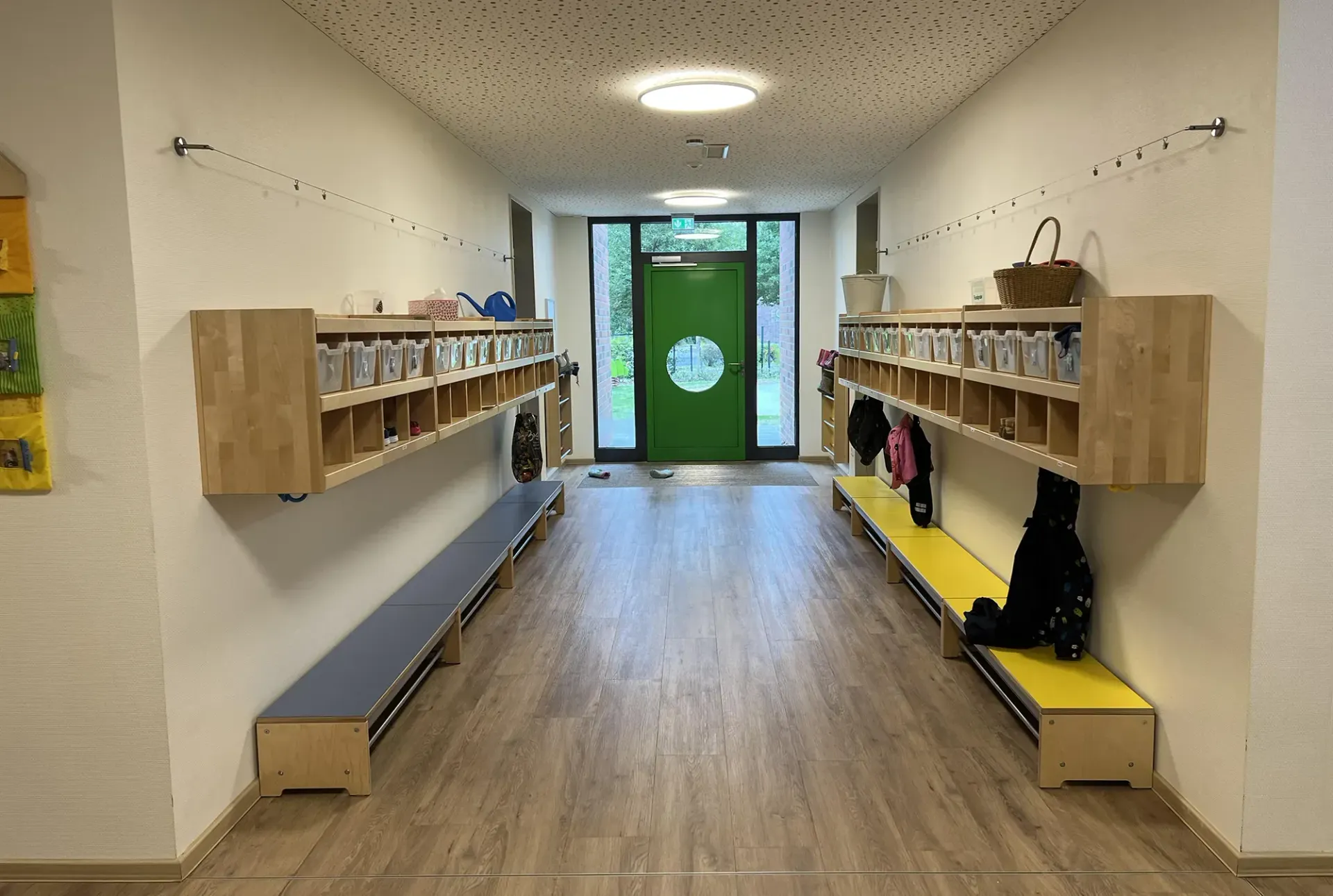 Ein Flur mit einer grünen Tür und Holzbänken