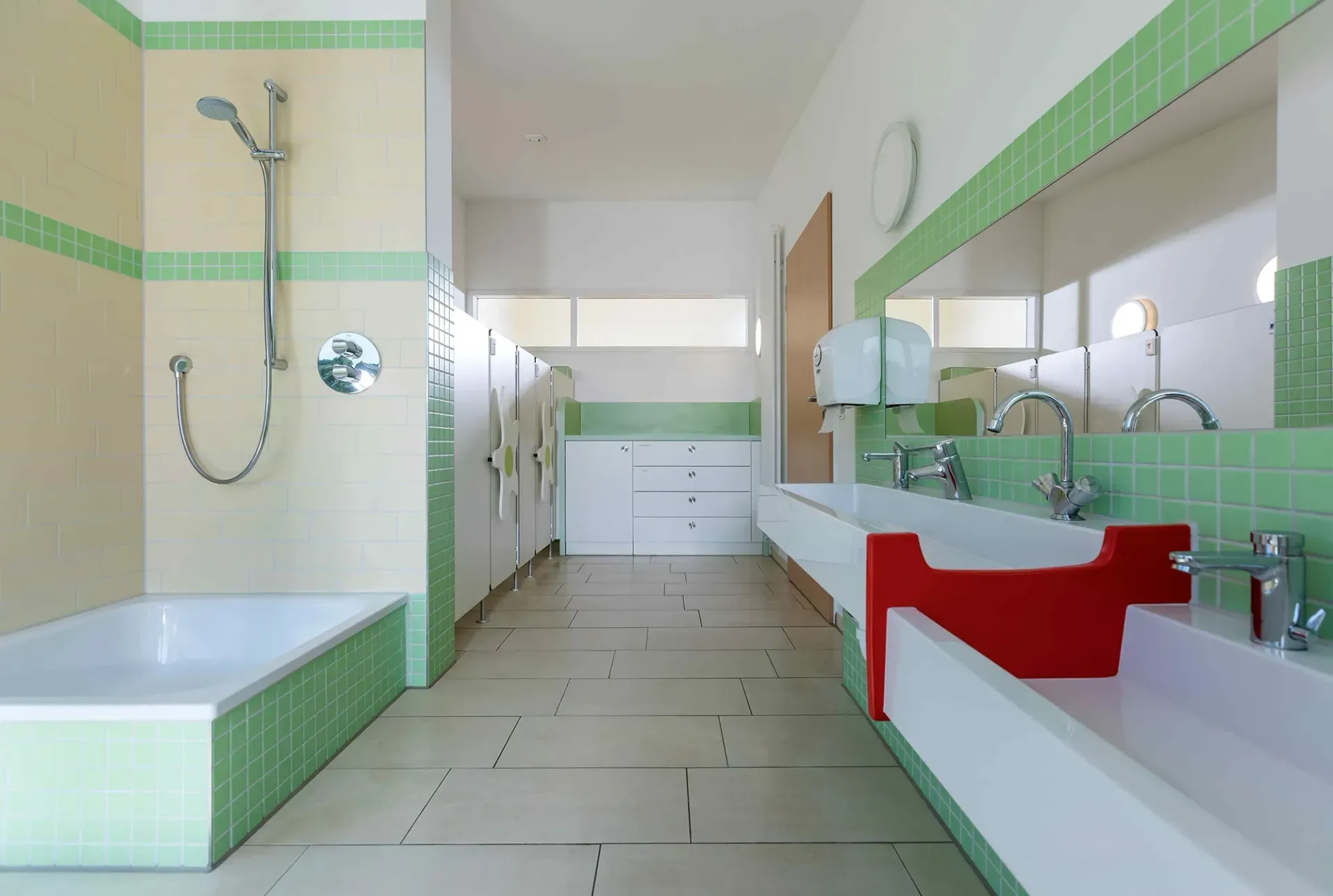 Ein Badezimmer mit grünen Fliesen und einem roten Waschbecken