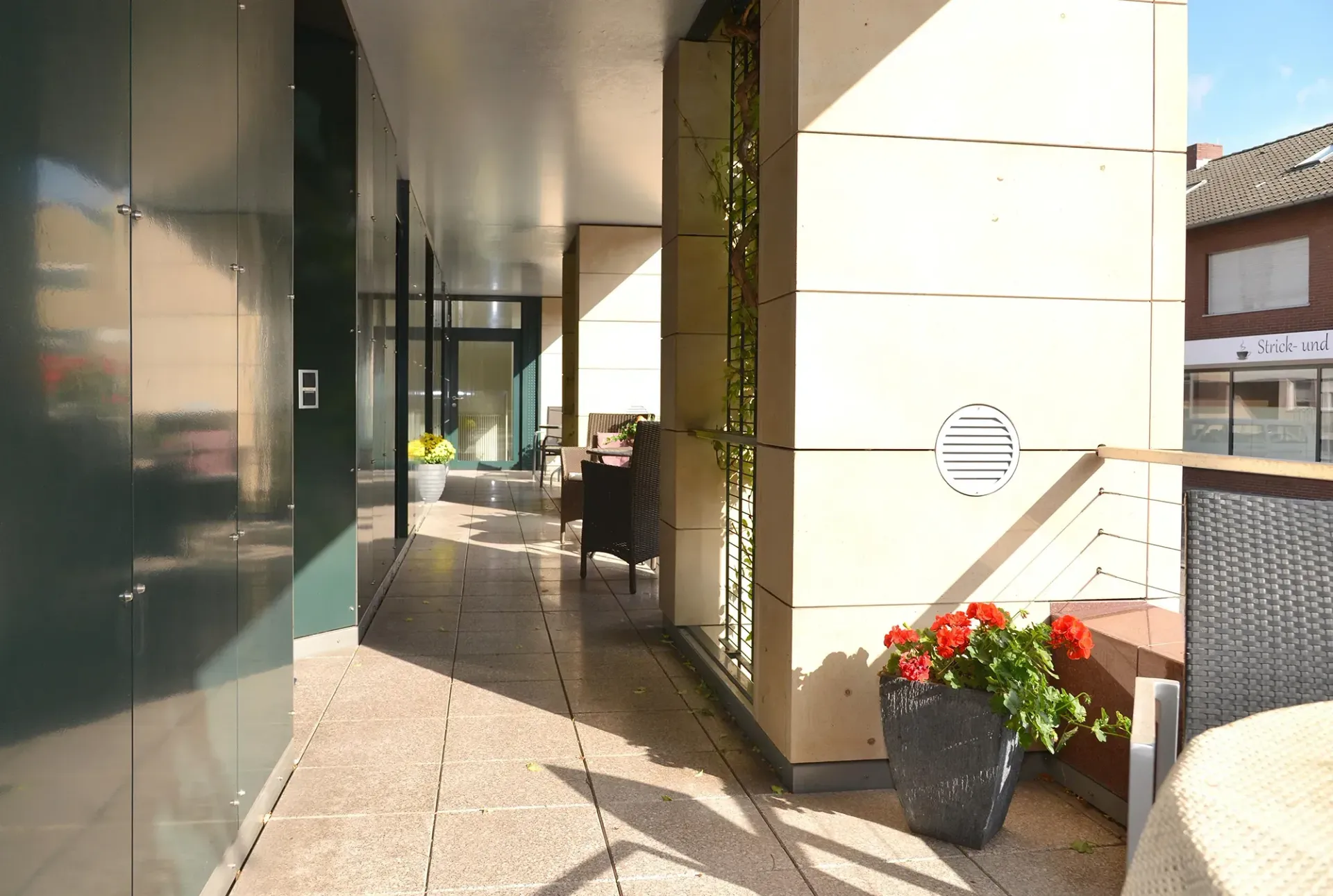 Ein Blumentopf mit roten Blumen steht auf einem Balkon vor einem Gebäude