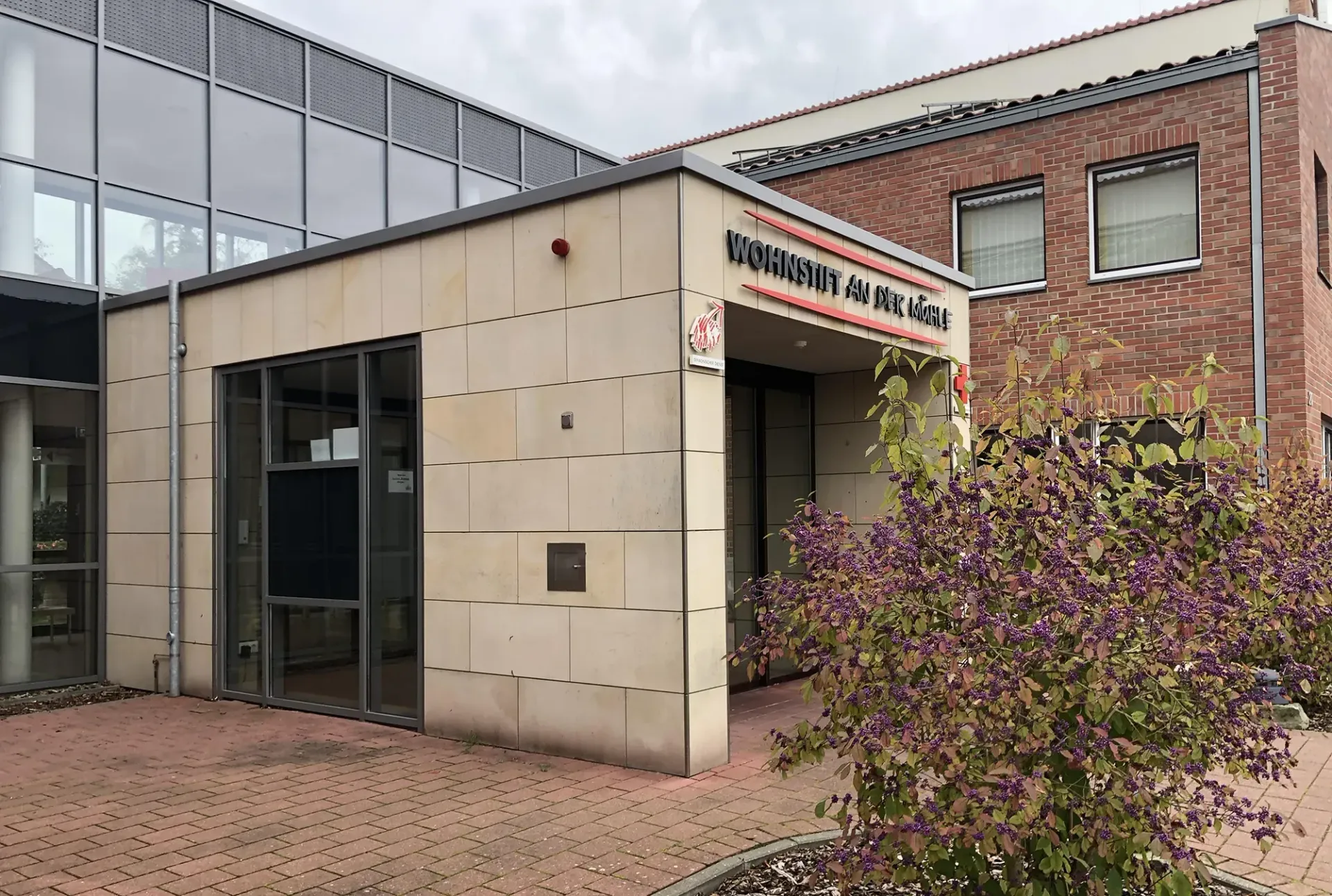 Ein Backsteingebäude mit einem lila Busch davor
