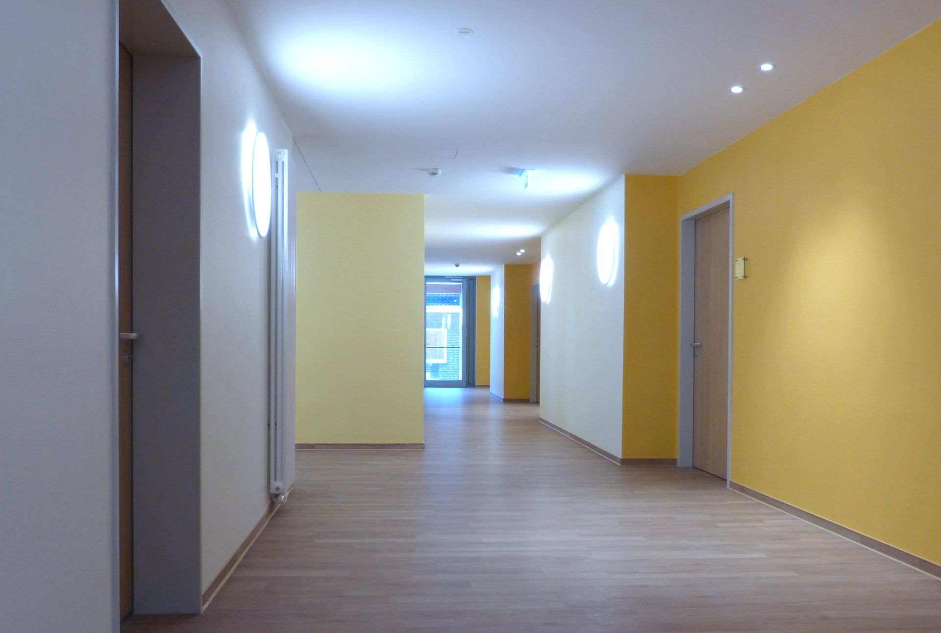 Ein leerer Flur mit gelben Wänden und Holzböden