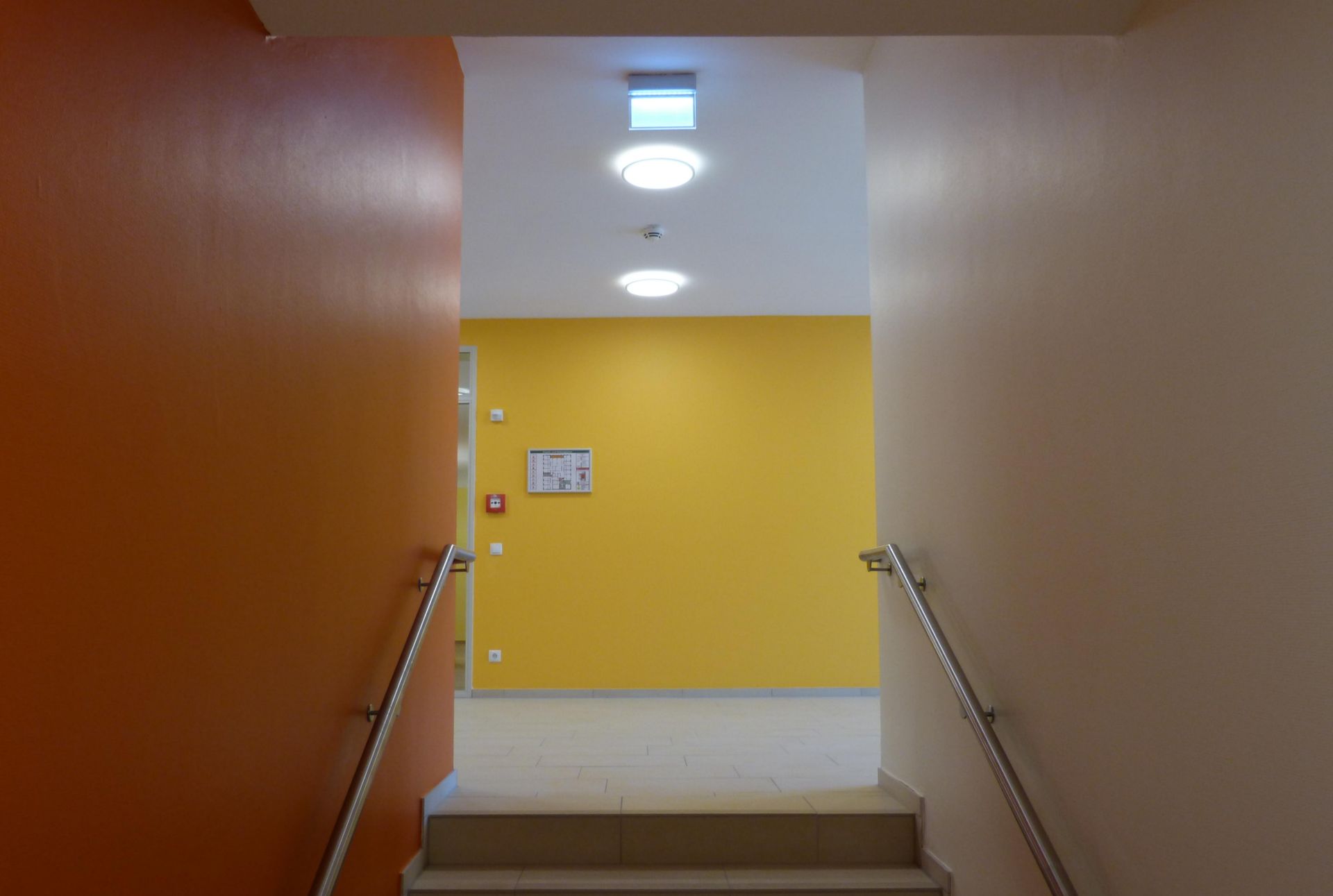 Ein Flur mit einer Treppe, die zu einer gelben Wand hinaufführt.