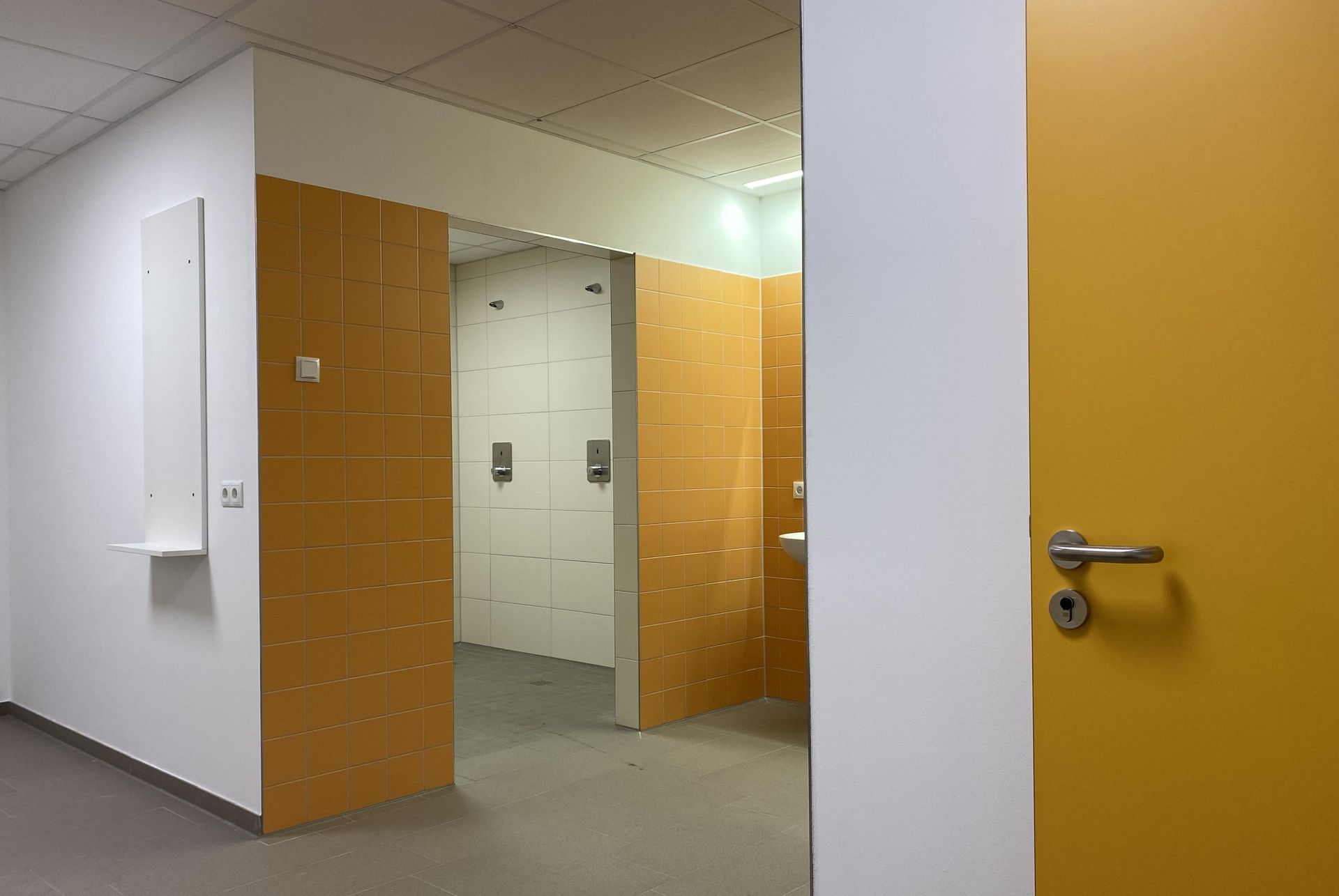 Ein Flur mit einer gelben Tür, die zu einem Umkleideraum führt.
