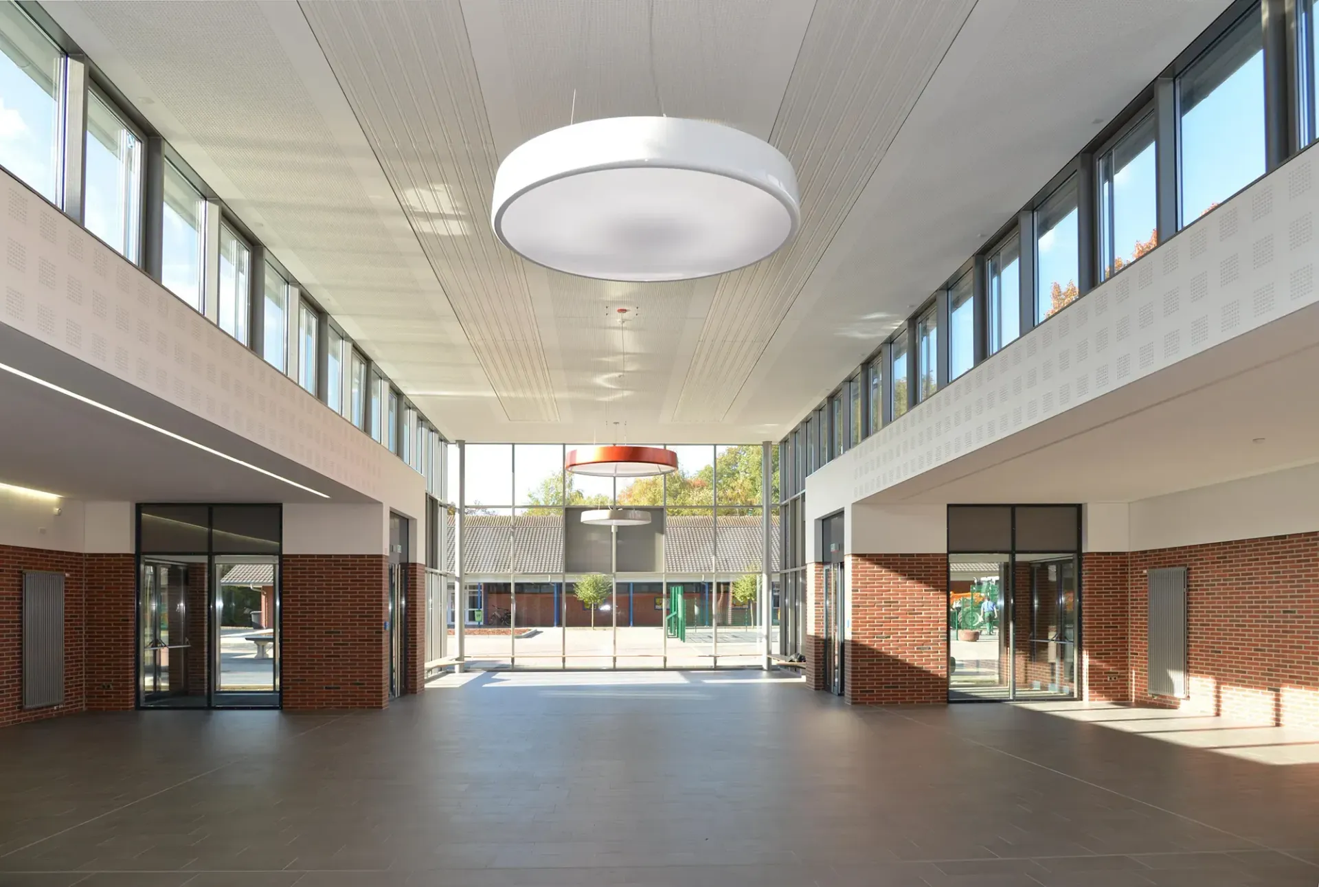 Ein großer Raum mit vielen Fenstern und einer Lampe, die von der Decke hängt.