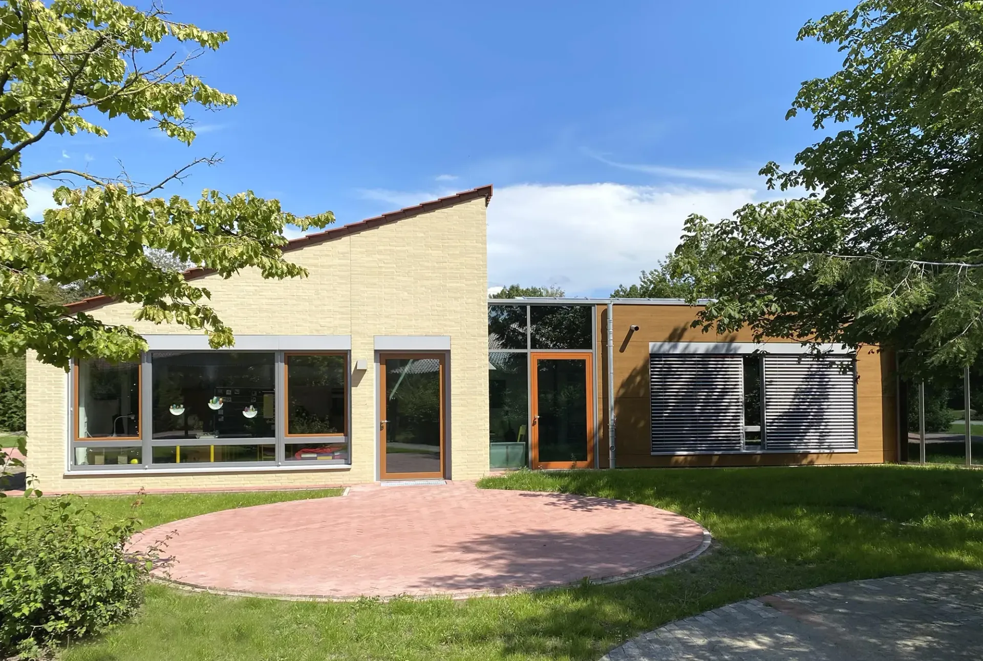 Ein großes Gebäude mit vielen Fenstern ist von Gras und Bäumen umgeben