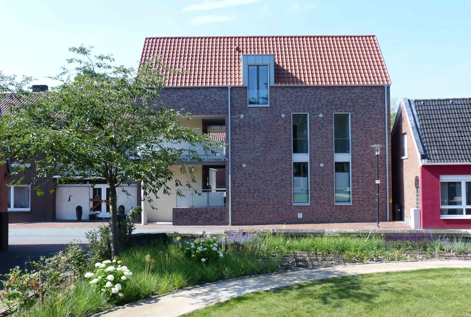 Ein Backsteinhaus mit einem roten Ziegeldach steht neben einem roten Haus