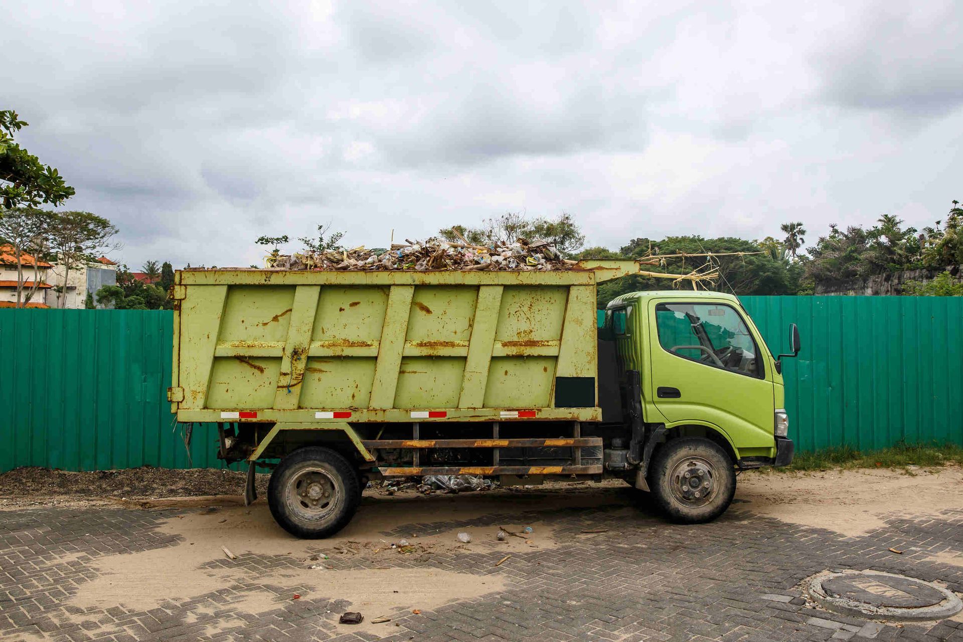 Un camión volquete verde está estacionado frente a una valla verde.