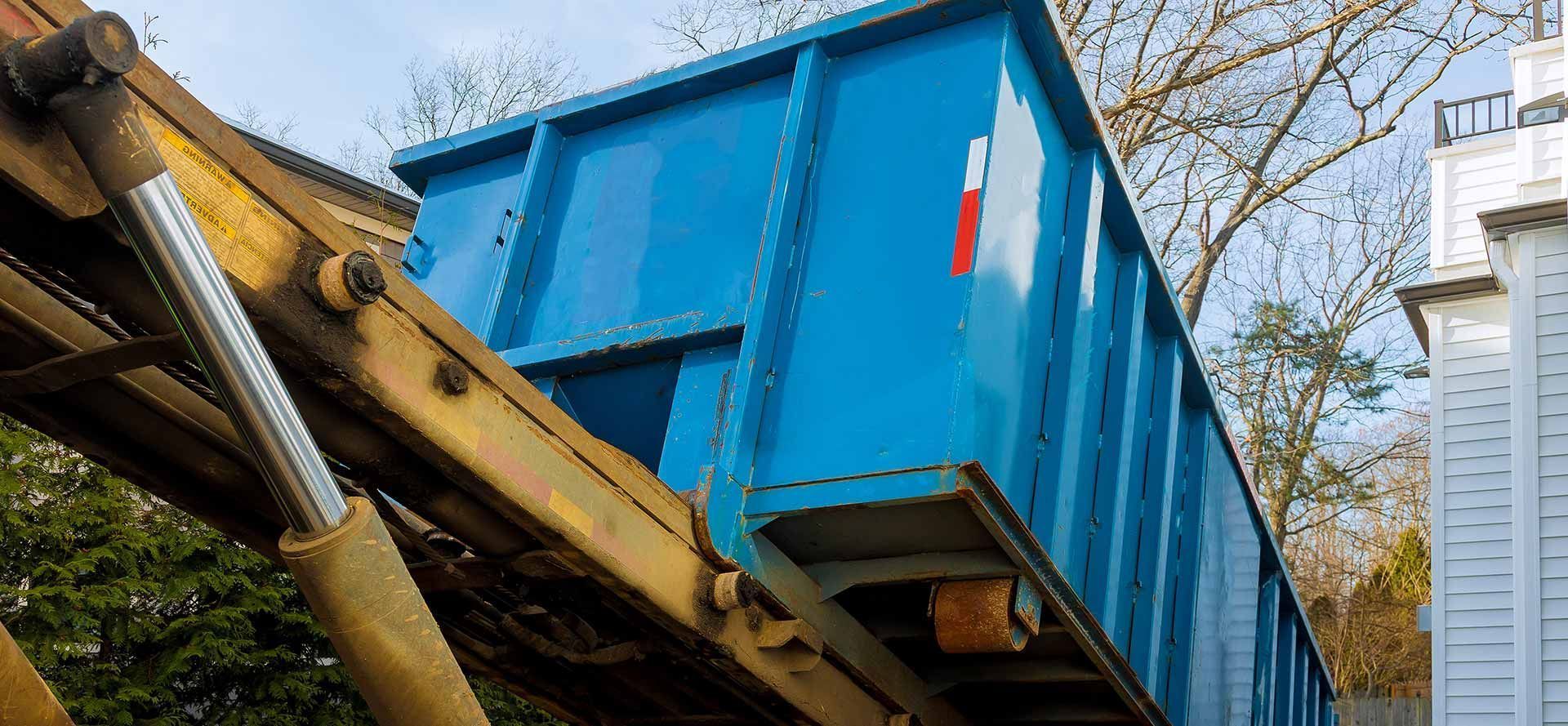 Un contenedor azul está siendo levantado por una grúa.