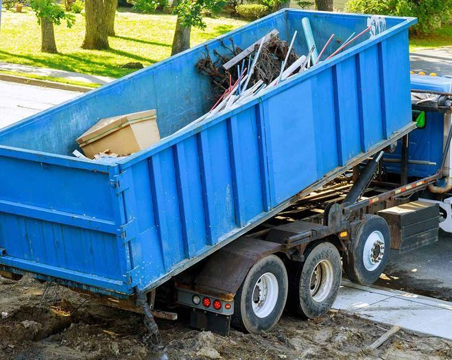 Un camión contenedor de basura azul está estacionado al costado de la carretera.