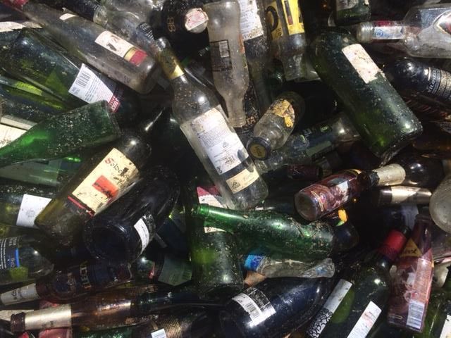 Una pila de botellas de vino vacías se apilan una encima de otra.