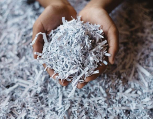 Una persona sostiene una pila de papel triturado en sus manos.